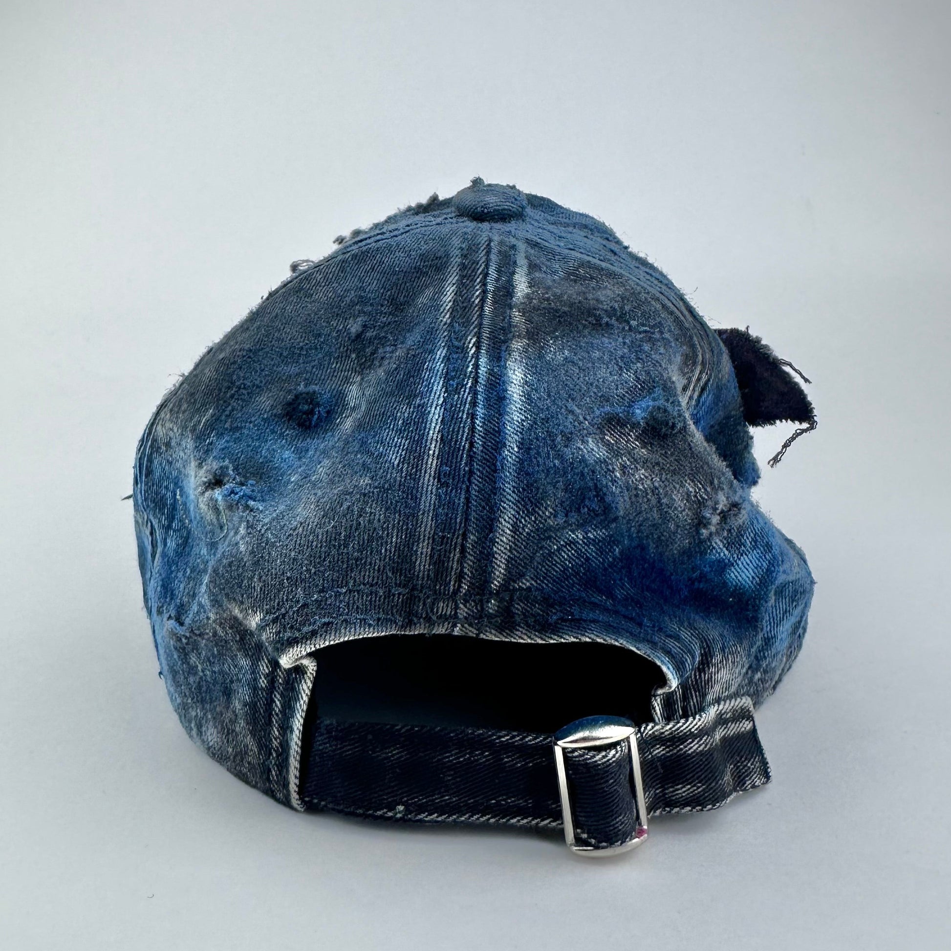 Back of ASTROBOI* Nebulous Cloud black hat with rainbow airbrush denim, safety pins and silver steel piercings on distressed grunge design.