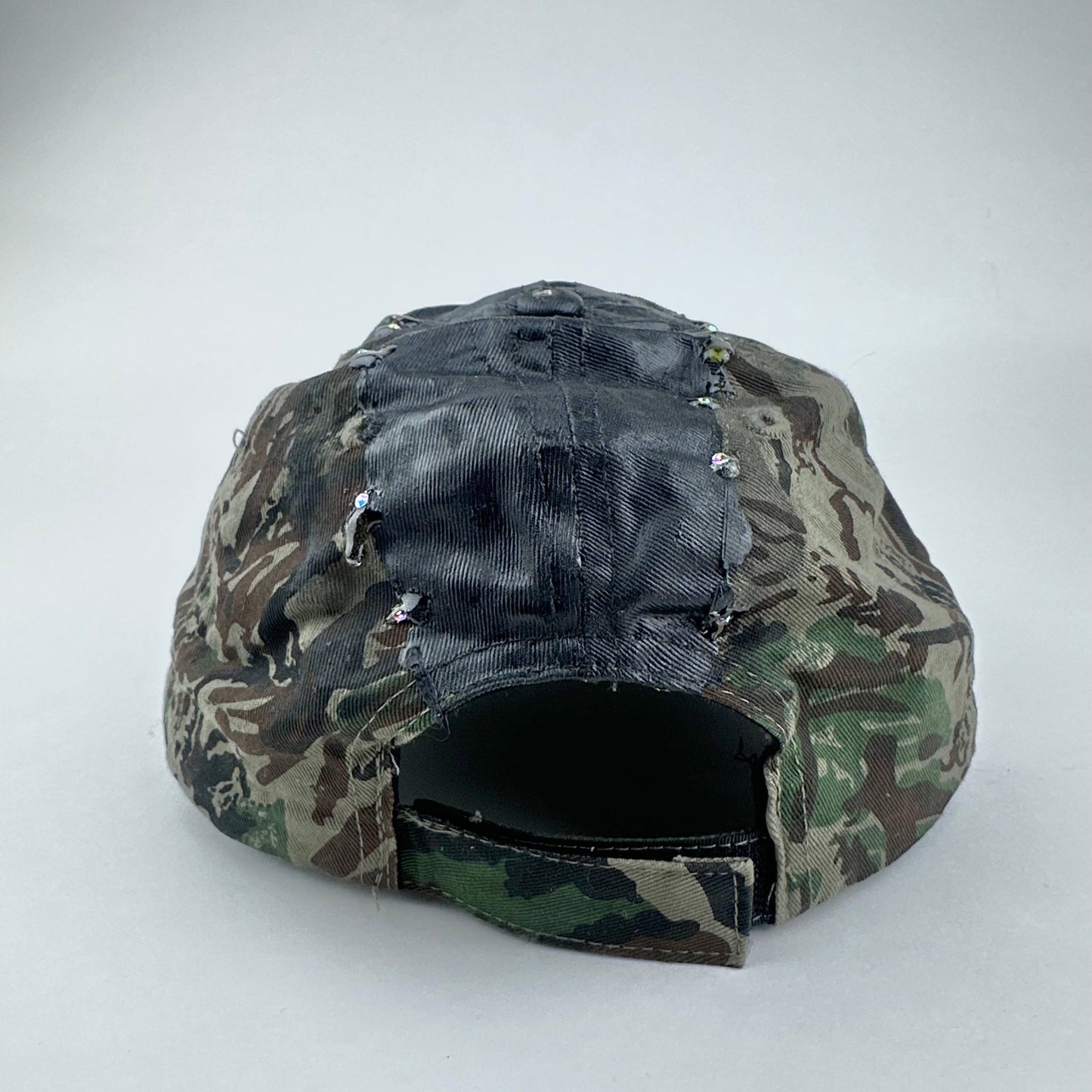 Flat back of ASTROBOI* L&L Supply green RealTree camo utility hat with purple and green rhinestones sealed in resin and black tattoo print detailing