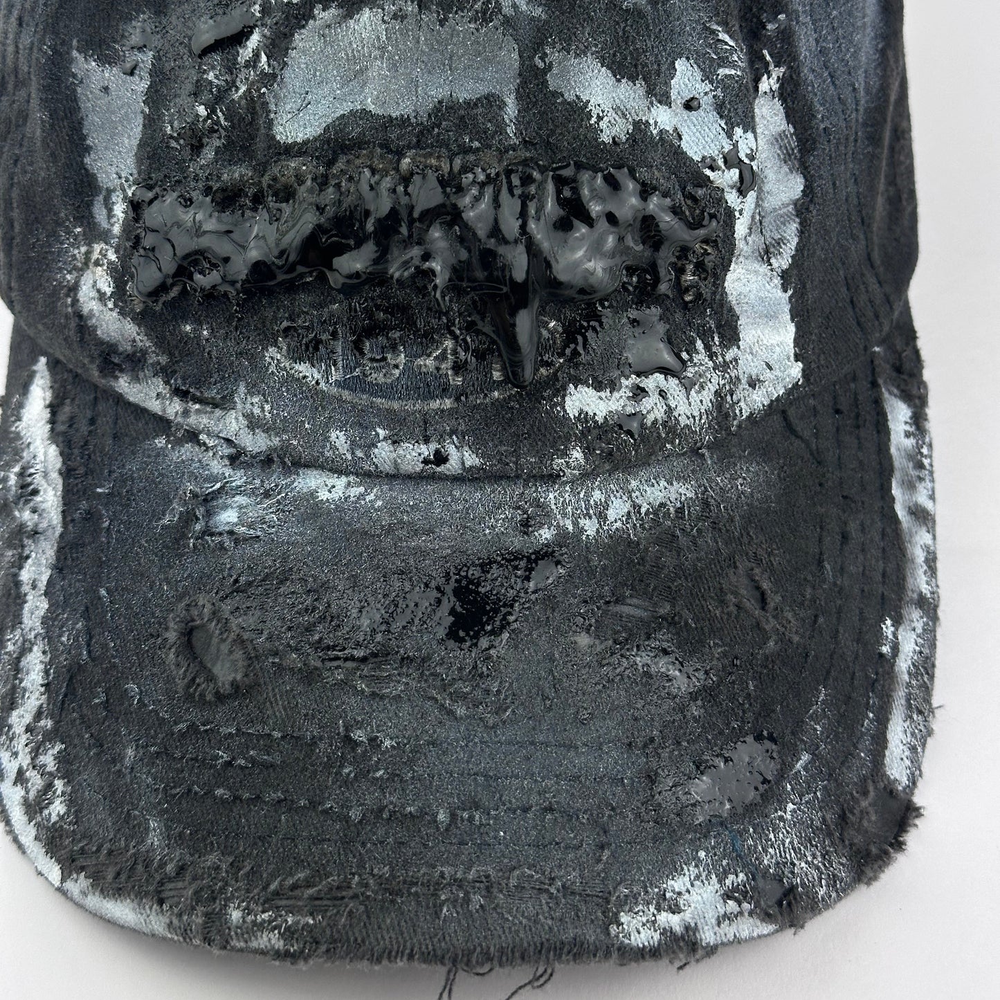 Close up of logo and visor detail on ASTROBOI* Brooklyn distressed black baseball hat with 3D black resin slime over embroidery and adjustable back strap, handmade in NYC.