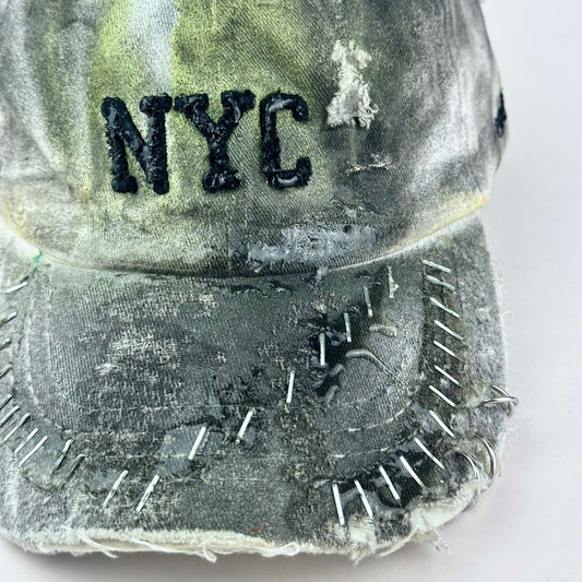 Front flat lay detail on ASTROBOI* white NYC dad hat with clear resin logo, black and green abstract paint details, adjustable strap back