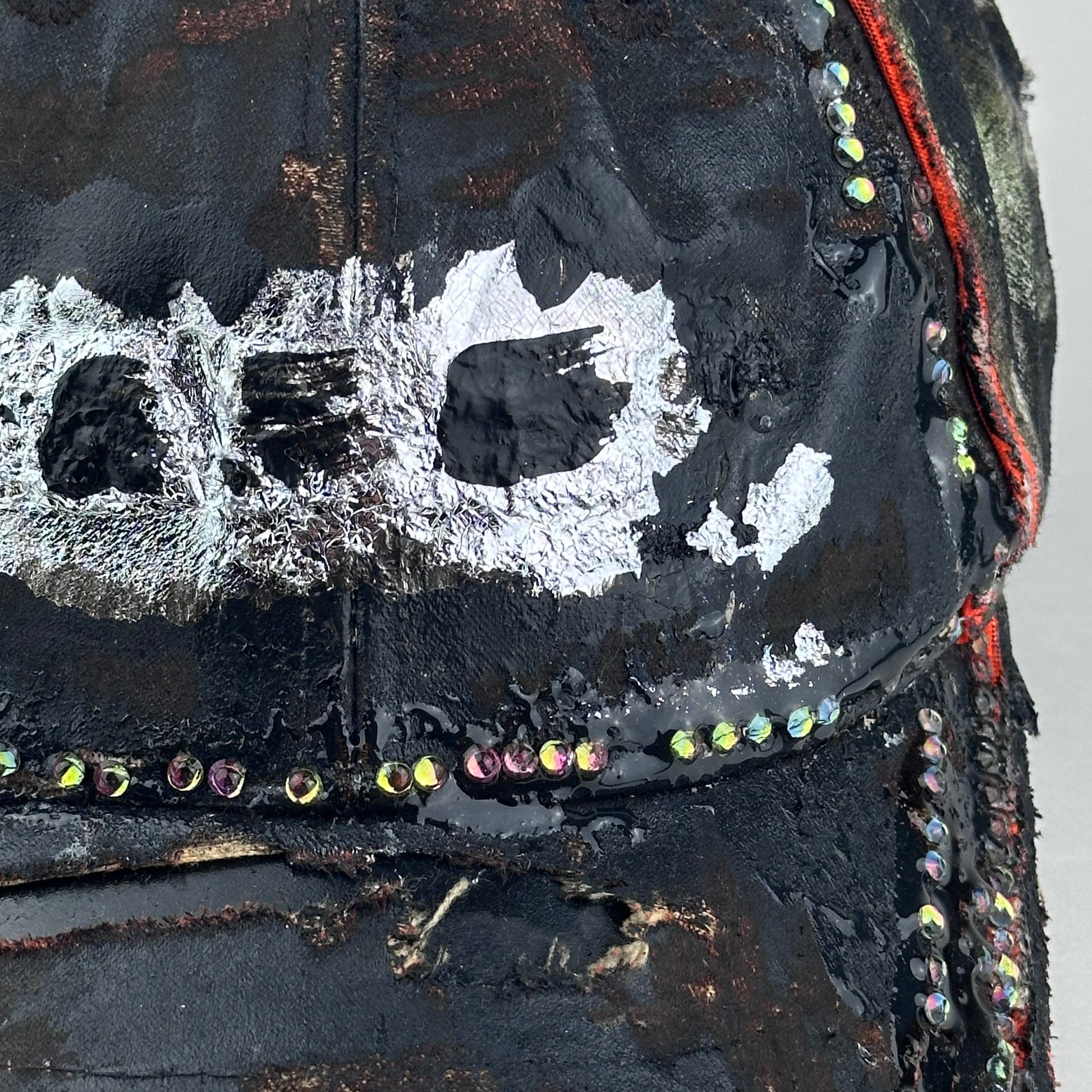 Flat front detail 2 of ASTROBOI* brown camouflage distressed hat with rhinestones sealed in clear resin and custom hand-painted detailing.