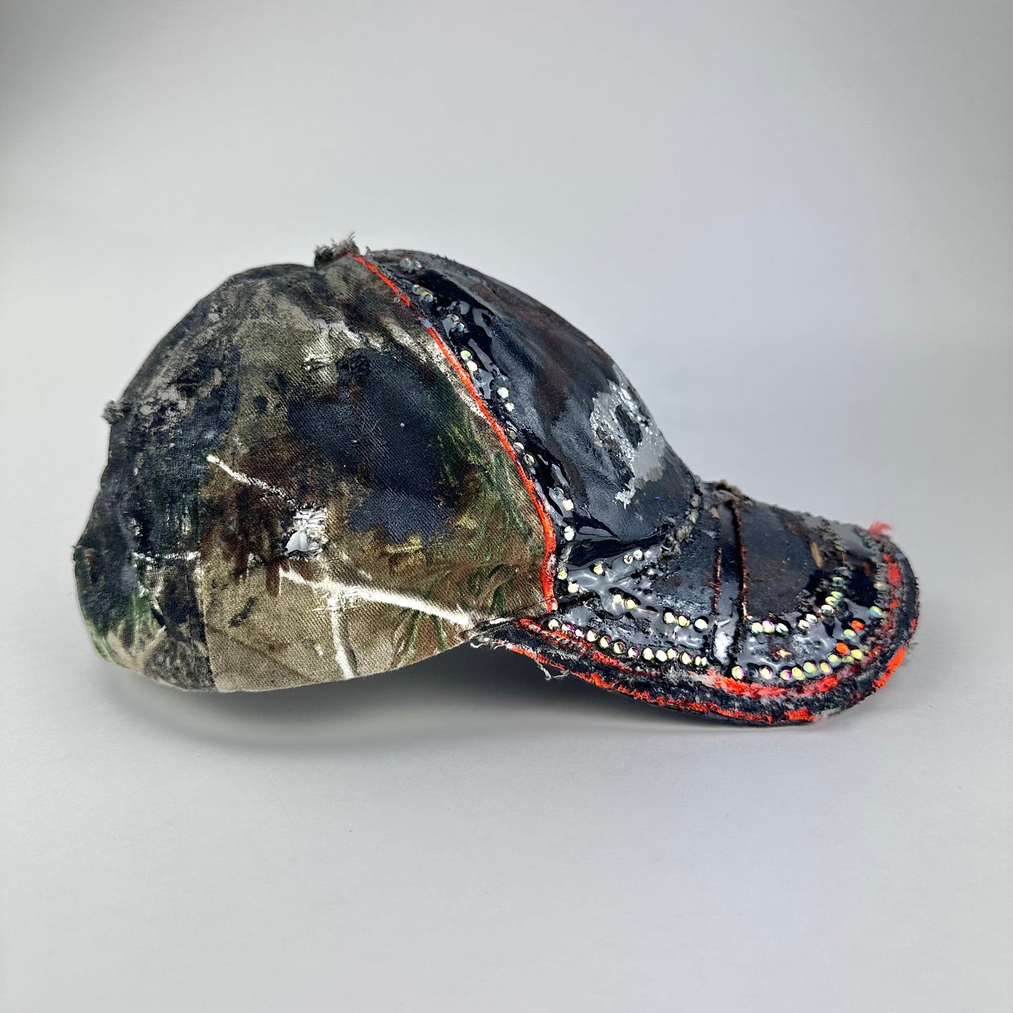 Flay front right on ASTROBOI* brown camouflage distressed hat with rhinestones sealed in clear resin and custom hand-painted detailing.