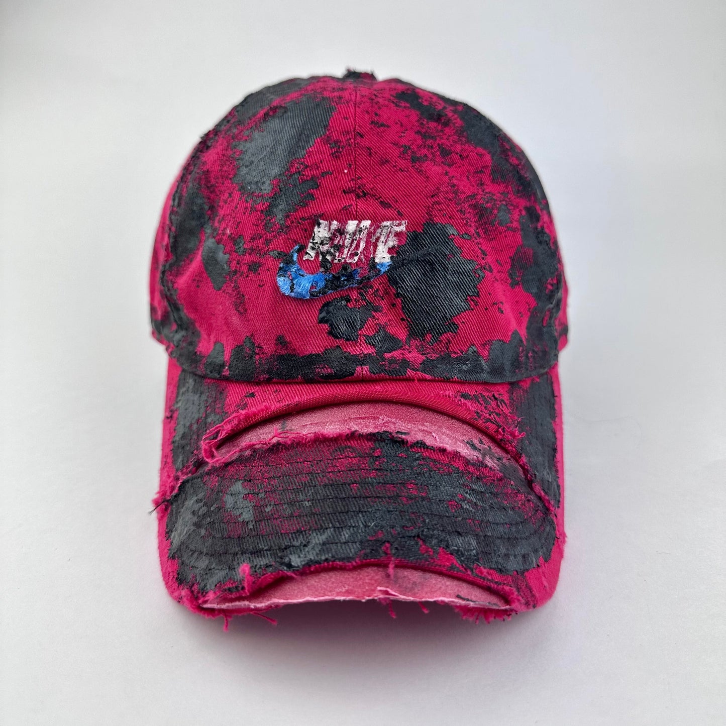 ASTROBOI* x Nike 'Comet' red and black painted distressed hat with Nike logo at center front and black painted pattern throughout, front view.