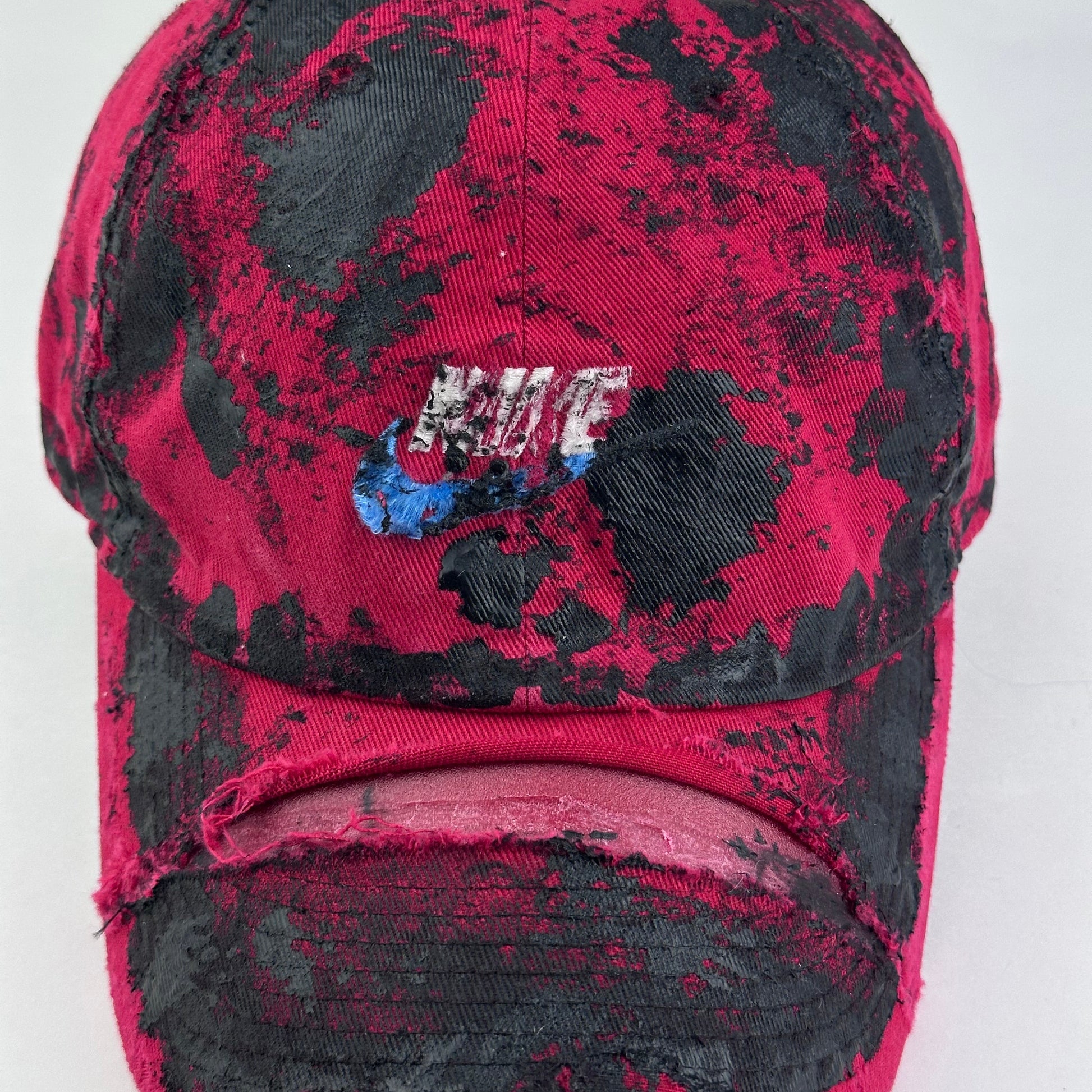 Close-up of ASTROBOI* x Nike 'Comet' showing Nike logo detail and black painted pattern on distressed red fabric.