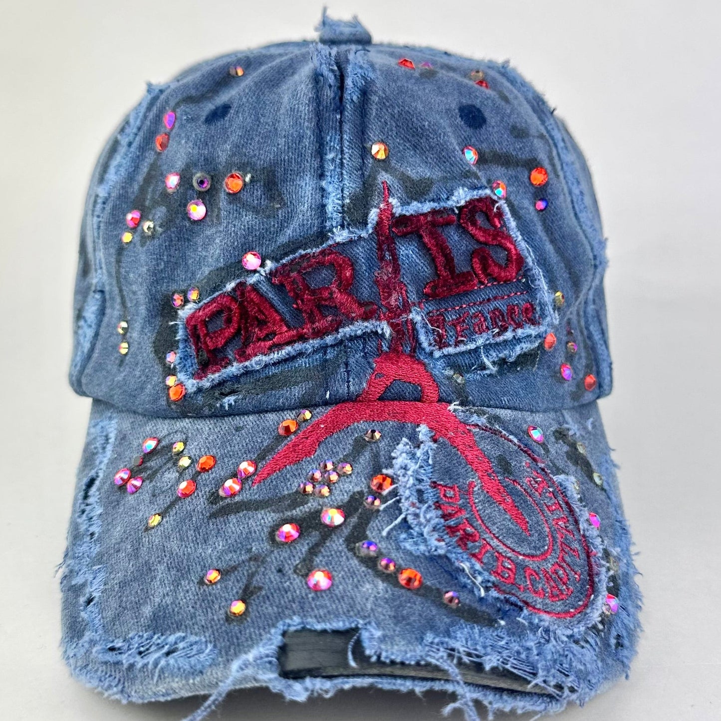 Front of ASTROBOI* Lights of Paris blue baseball hat with Eiffel Tower embroidery, black graffiti print and red orange rhinestone crystals.