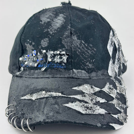 Front flay lay of of ASTROBOI* Speed Racing black and white checkered utility hat with resin-set rhinestones, stainless steel piercings, and hand-painted detailing