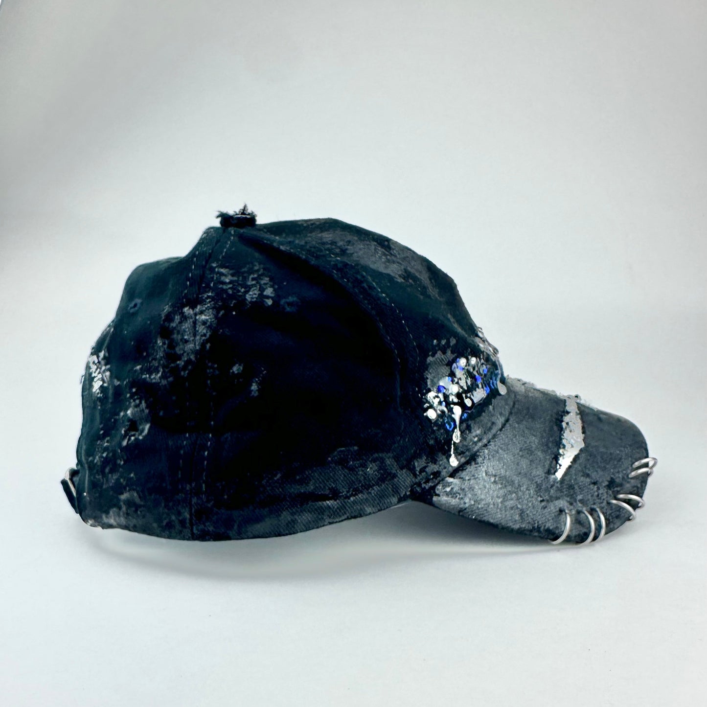Flay lay right on ASTROBOI* Speed Racing black and white checkered utility hat with resin-set rhinestones, stainless steel piercings, and hand-painted detailing
