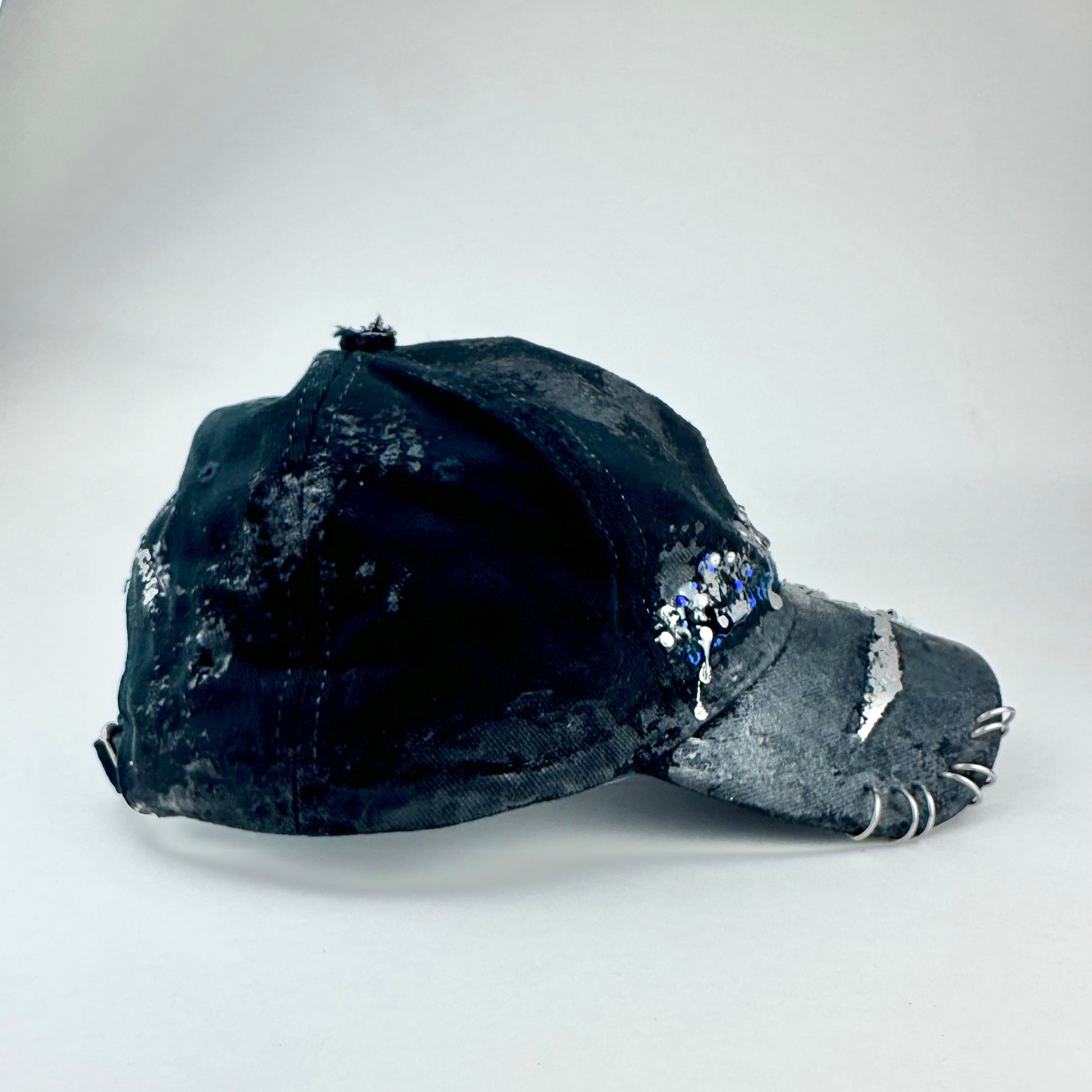 Flay lay right on ASTROBOI* Speed Racing black and white checkered utility hat with resin-set rhinestones, stainless steel piercings, and hand-painted detailing