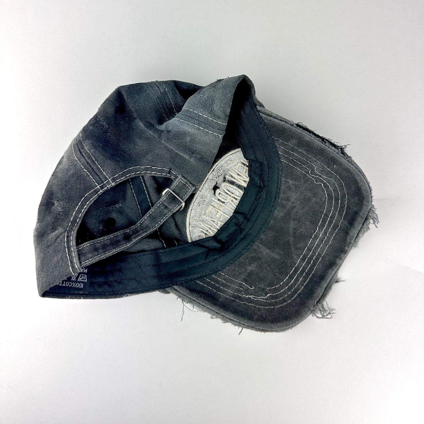 Back side of ASTROBOI* Technicolor black distressed hat with multicolor metallic New Orleans logo, rhinestones sealed in resin and ripped visor detail.