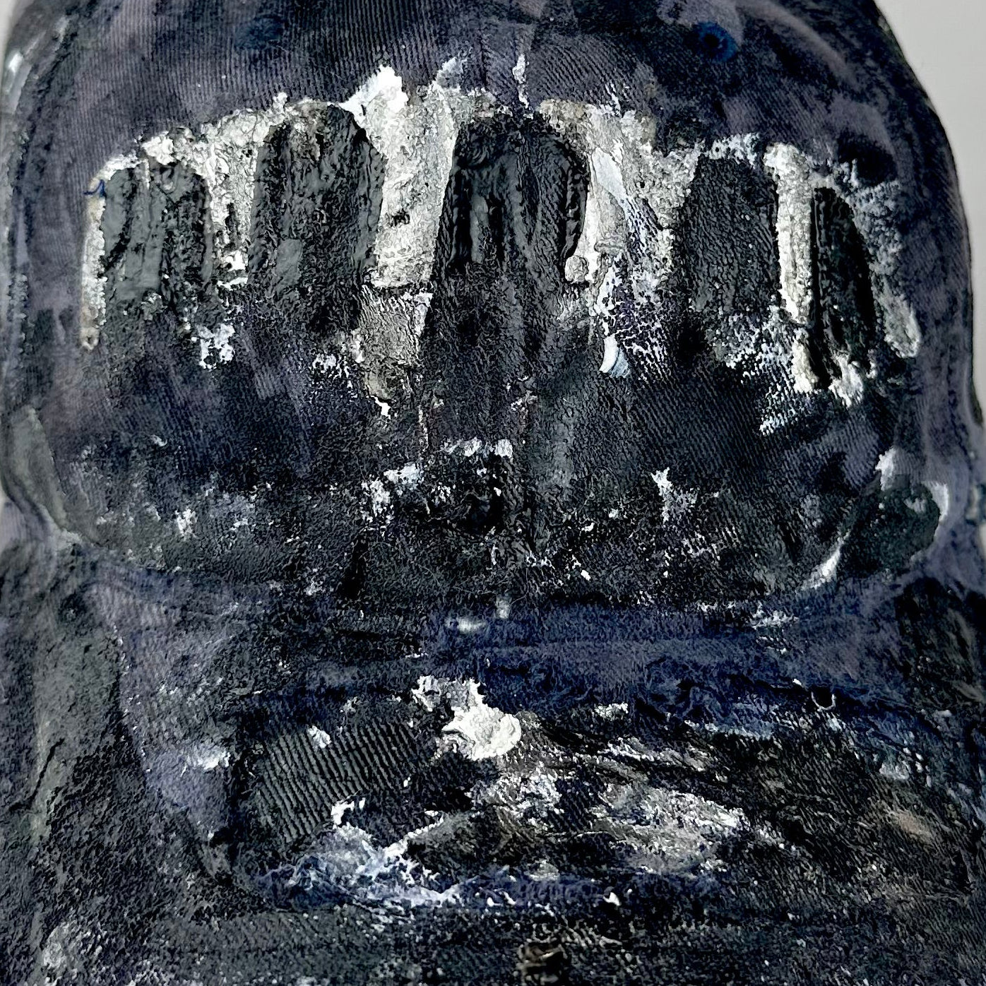 Close up of ASTROBOI* navy fitted cap with custom black, white, and silver paint and distressed vintage finish.