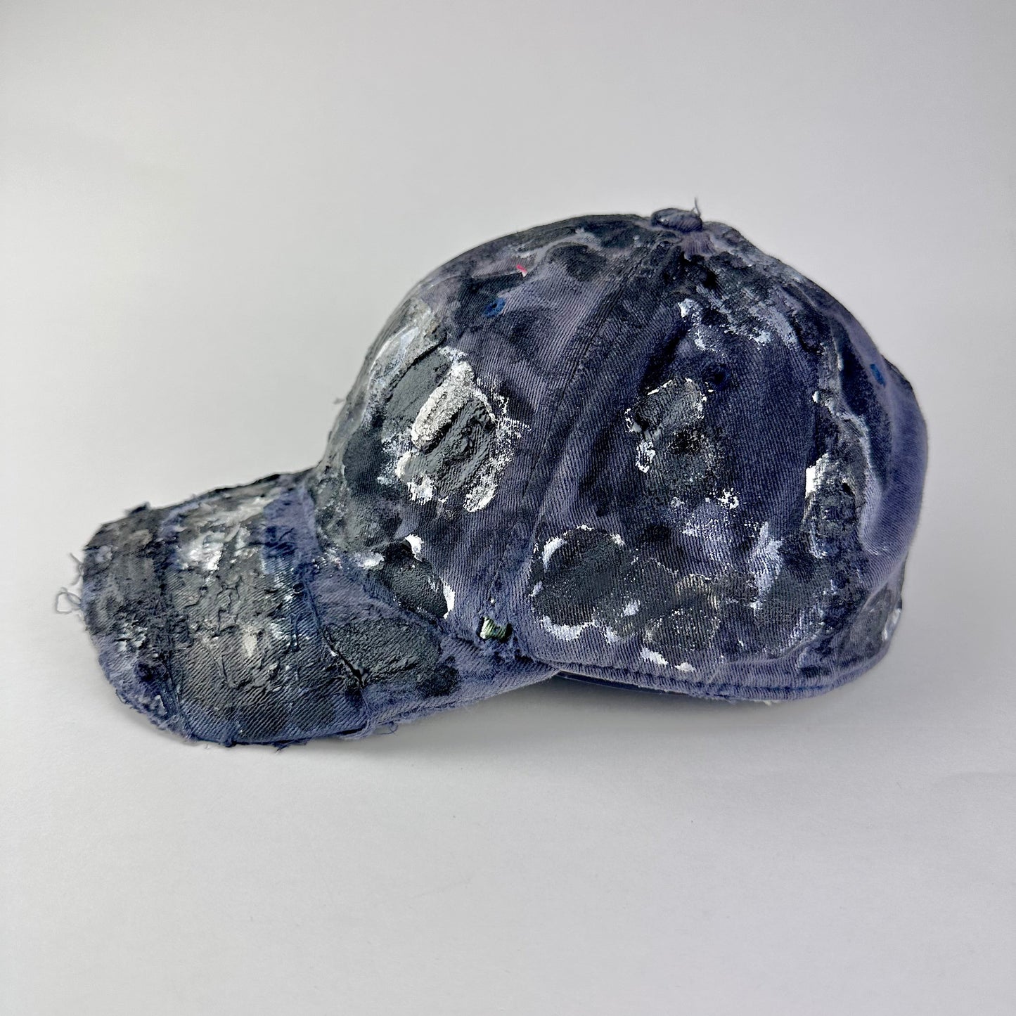 Left side of ASTROBOI* navy fitted cap with custom black, white, and silver paint and distressed vintage finish.