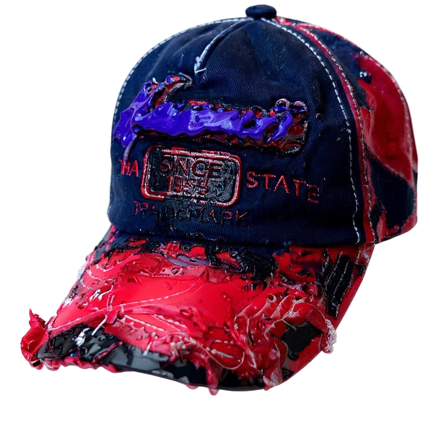 Flat lay of Blue and red ASTROBOI* hat featuring a purple resin-coated Hawaii graphic, deconstructed visor with clear resin, and black painted accents.