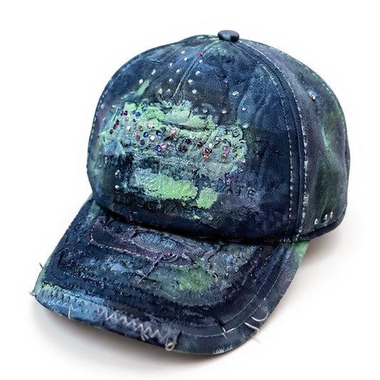 3D image of “Green and brown distressed ASTROBOI* Hawaii hat with rhinestones, metallic paint, and sterling-steel piercings, customized in NYC.”
