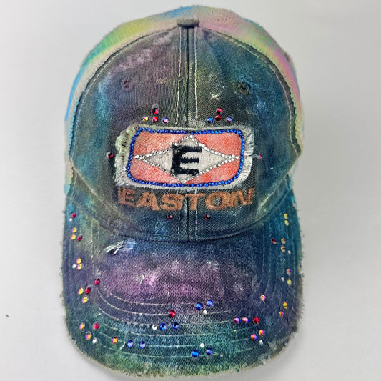 Front of ASTROBOI* EASTON rainbow rhinestone mesh trucker hat with airbrushed confetti design, sparkling logo, and adjustable back strap.