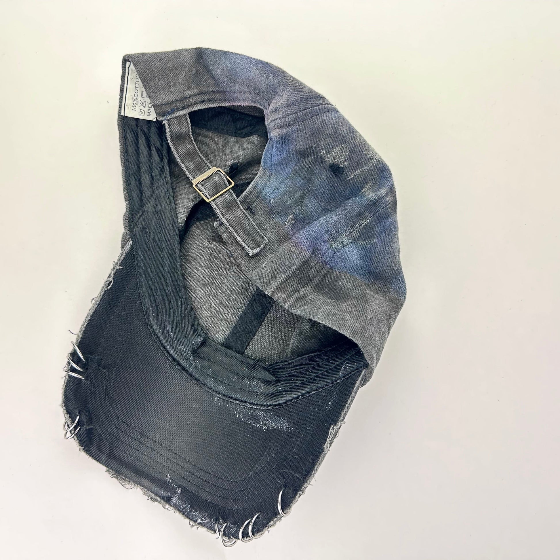 Back of ASTROBOI* distressed black Brooklyn hat with metallic purple paint, multicolored rhinestones, green airbrush shading, and white front lettering.