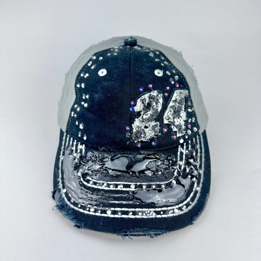 Front of ASTROBOI* “24” black racing cap with silver rhinestones, white stitching, glossy black resin details, and adjustable Velcro back closure.