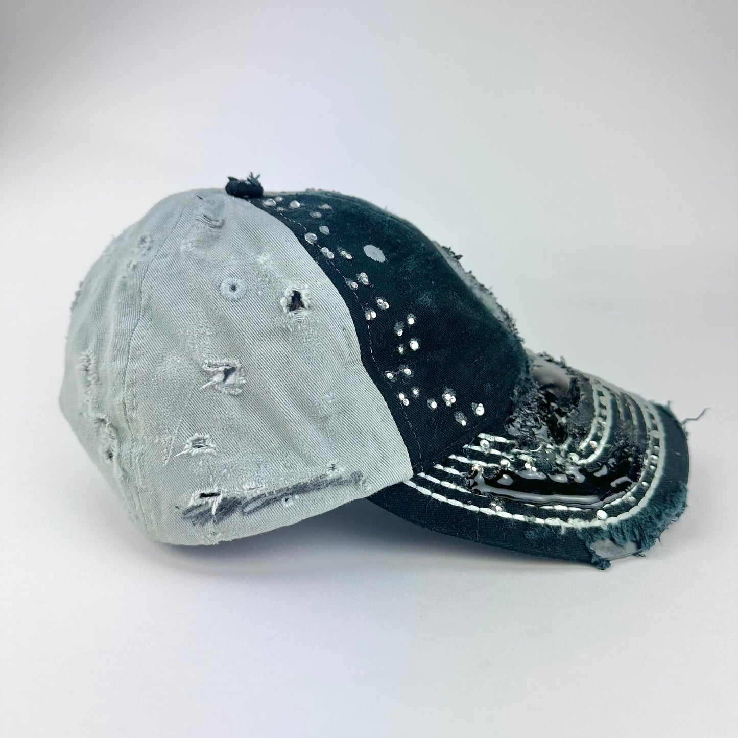 Right side of ASTROBOI* “24” black racing cap with silver rhinestones, white stitching, glossy black resin details, and adjustable Velcro back closure.
