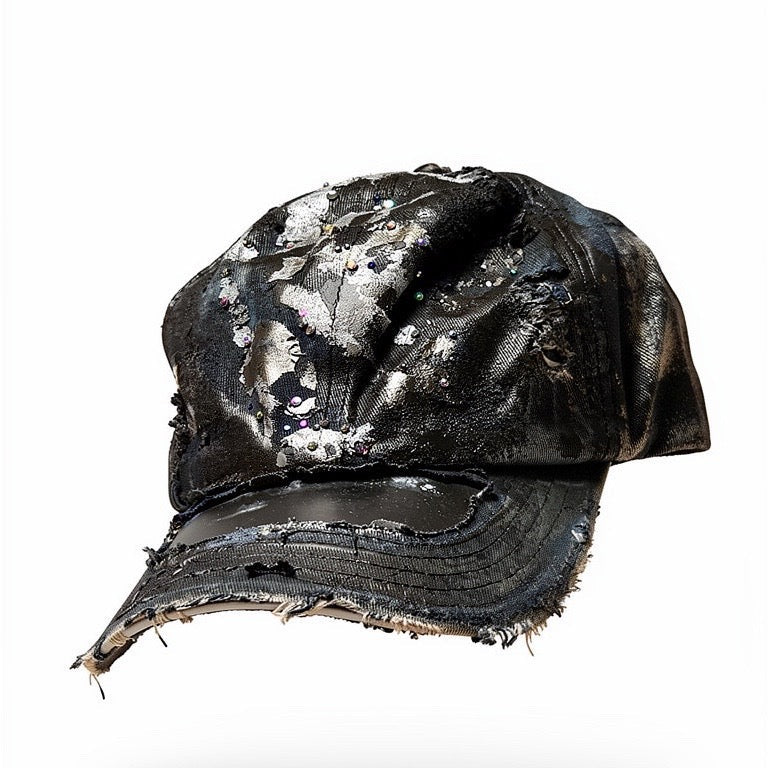 3d image of Black acid-washed denim hat with silver paint accents, multicolored rhinestones, and a ripped visor seam, customized by ASTROBOI* STUDIO.