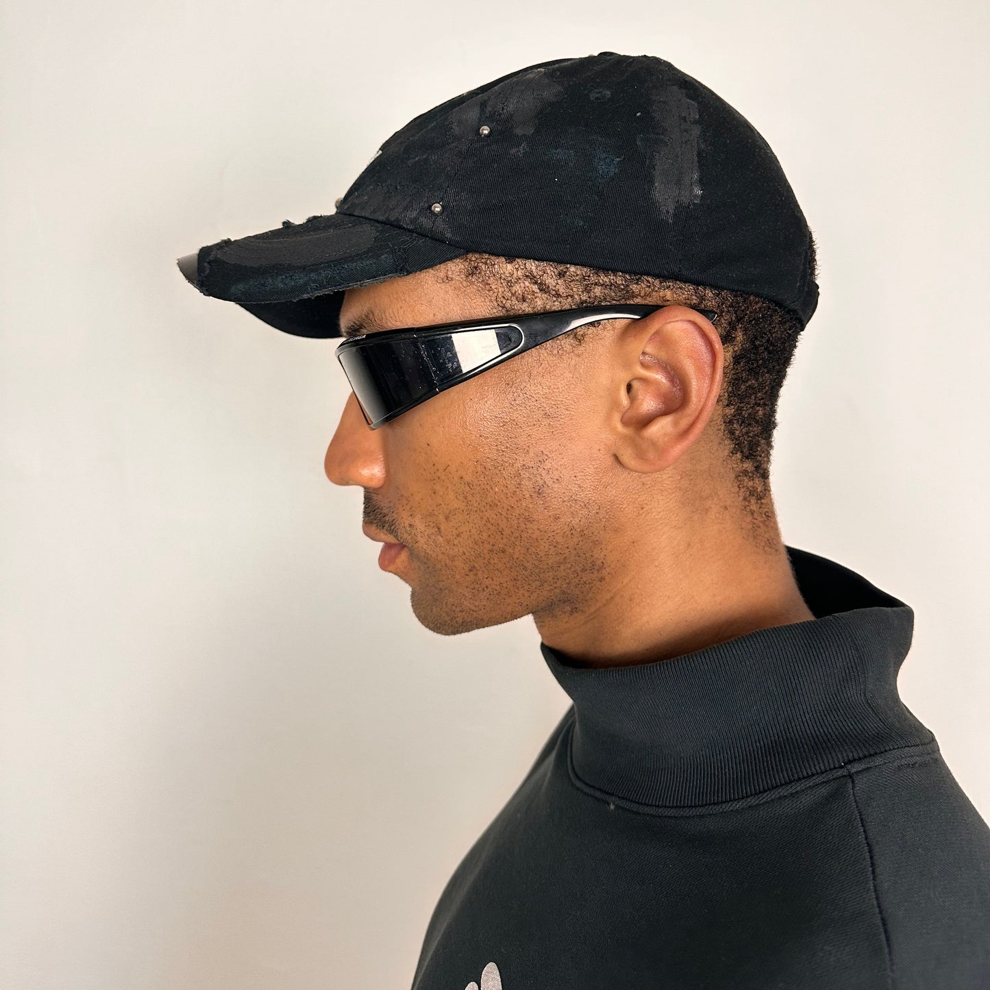 Left side of Black distressed ASTROBOI* ‘Daddy’ hat with custom paint detailing and stainless steel piercings, handcrafted in NYC.