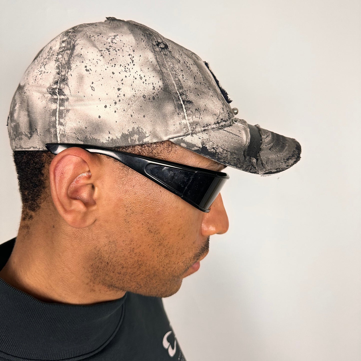 Right side of Off-white and black faded ASTROBOI* x Abercrombie hat with custom paint treatment and stainless steel piercing, handmade in NYC.