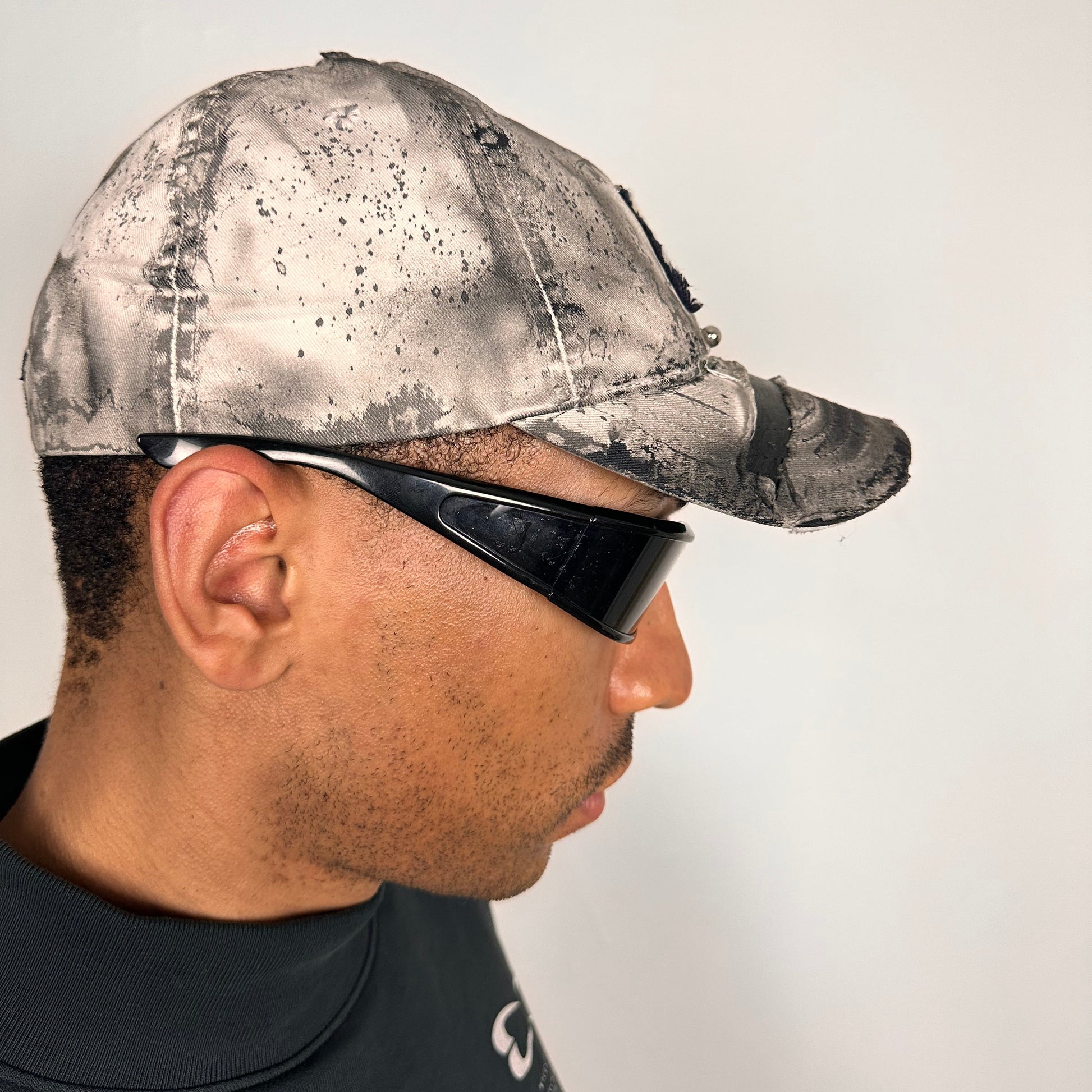 Right side of Off-white and black faded ASTROBOI* x Abercrombie hat with custom paint treatment and stainless steel piercing, handmade in NYC.