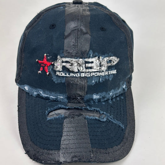 Close up product shot of ASTROBOI* RBP navy and black distressed utility hat with deconstructed visor, rhinestone logo sealed in resin, adjustable strap, custom NYC piece