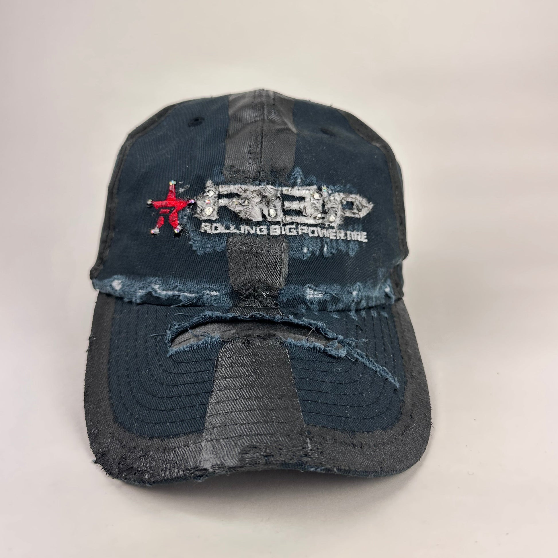 Front product shot of ASTROBOI* RBP navy and black distressed utility hat with deconstructed visor, rhinestone logo sealed in resin, adjustable strap, custom NYC piece