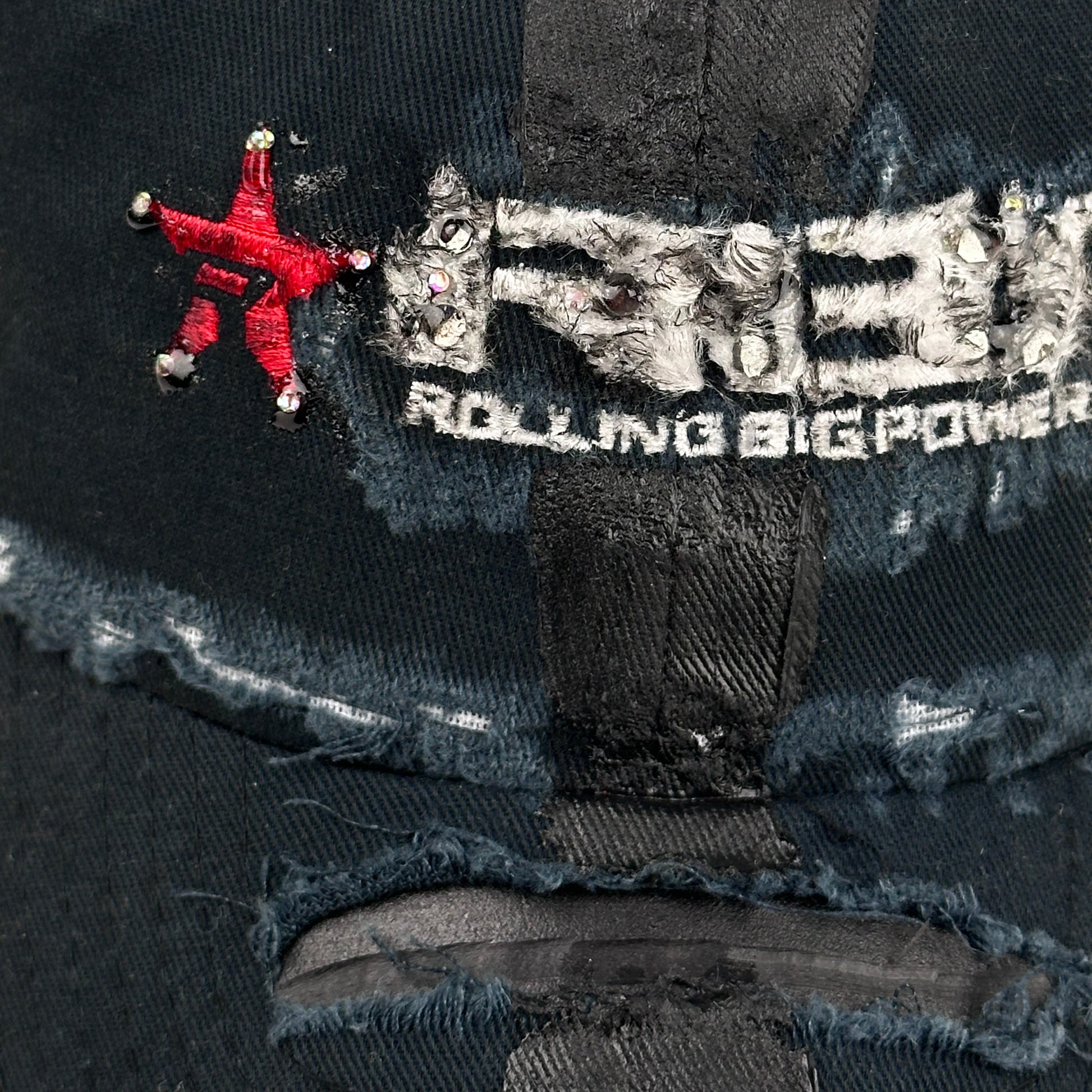 Close up product shot of ASTROBOI* RBP navy and black distressed utility hat with deconstructed visor, rhinestone logo sealed in resin, adjustable strap, custom NYC piece