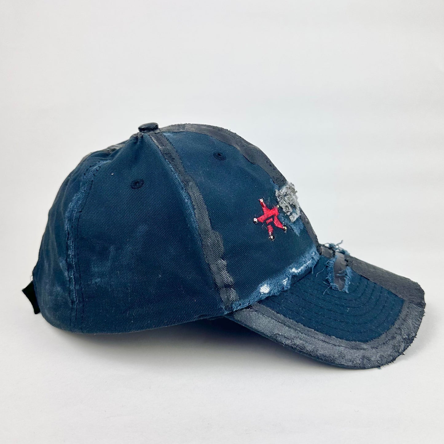 Left side product shot of ASTROBOI* RBP navy and black distressed utility hat with deconstructed visor, rhinestone logo sealed in resin, adjustable strap, custom NYC piece