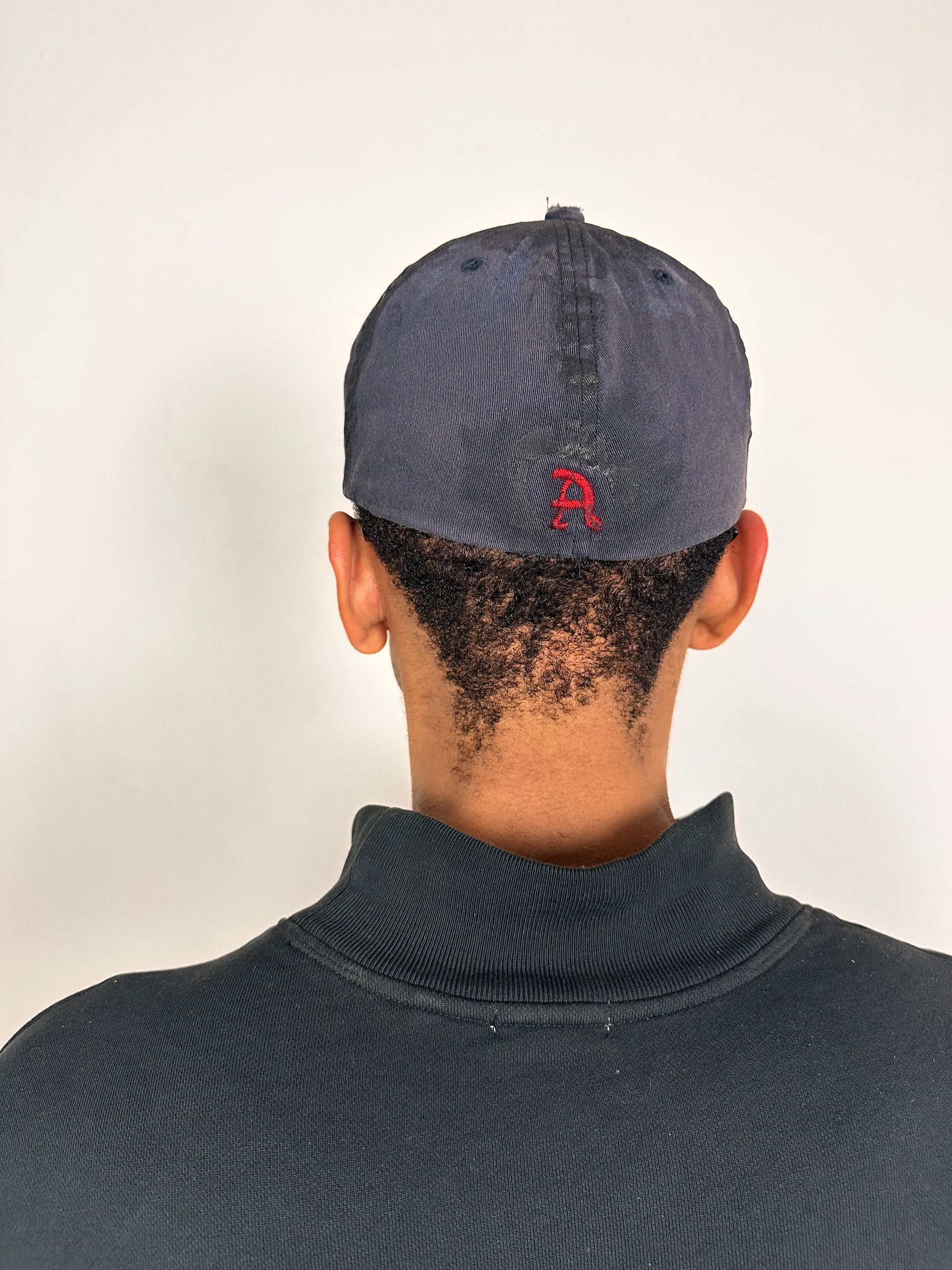 Back side of Navy ASTROBOI* x Abercrombie hat with distressed paint, stainless steel piercings, and logo embroidery on front and back, customized in NYC.