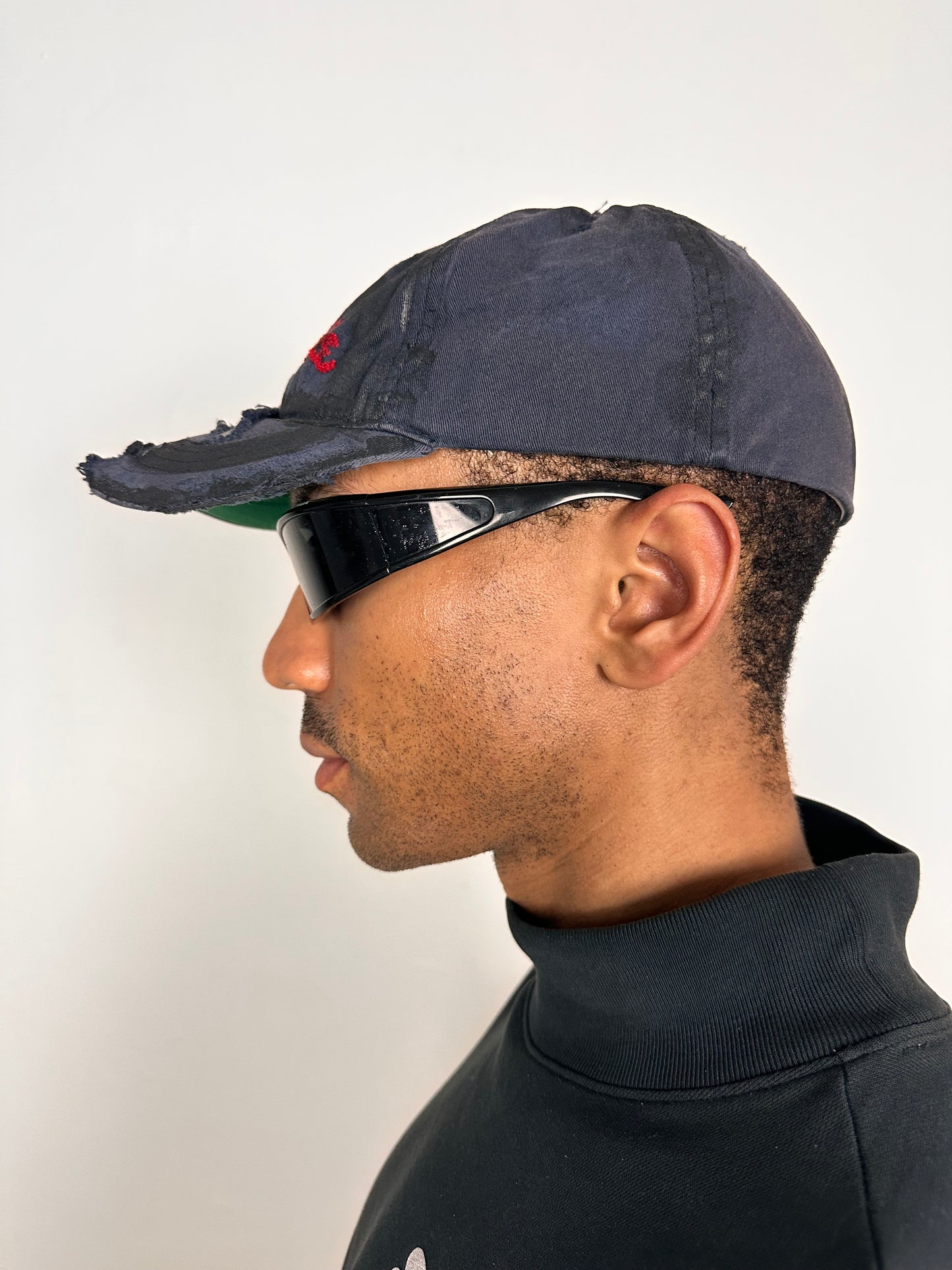 Left side of Navy ASTROBOI* x Abercrombie hat with distressed paint, stainless steel piercings, and logo embroidery on front and back, customized in NYC.