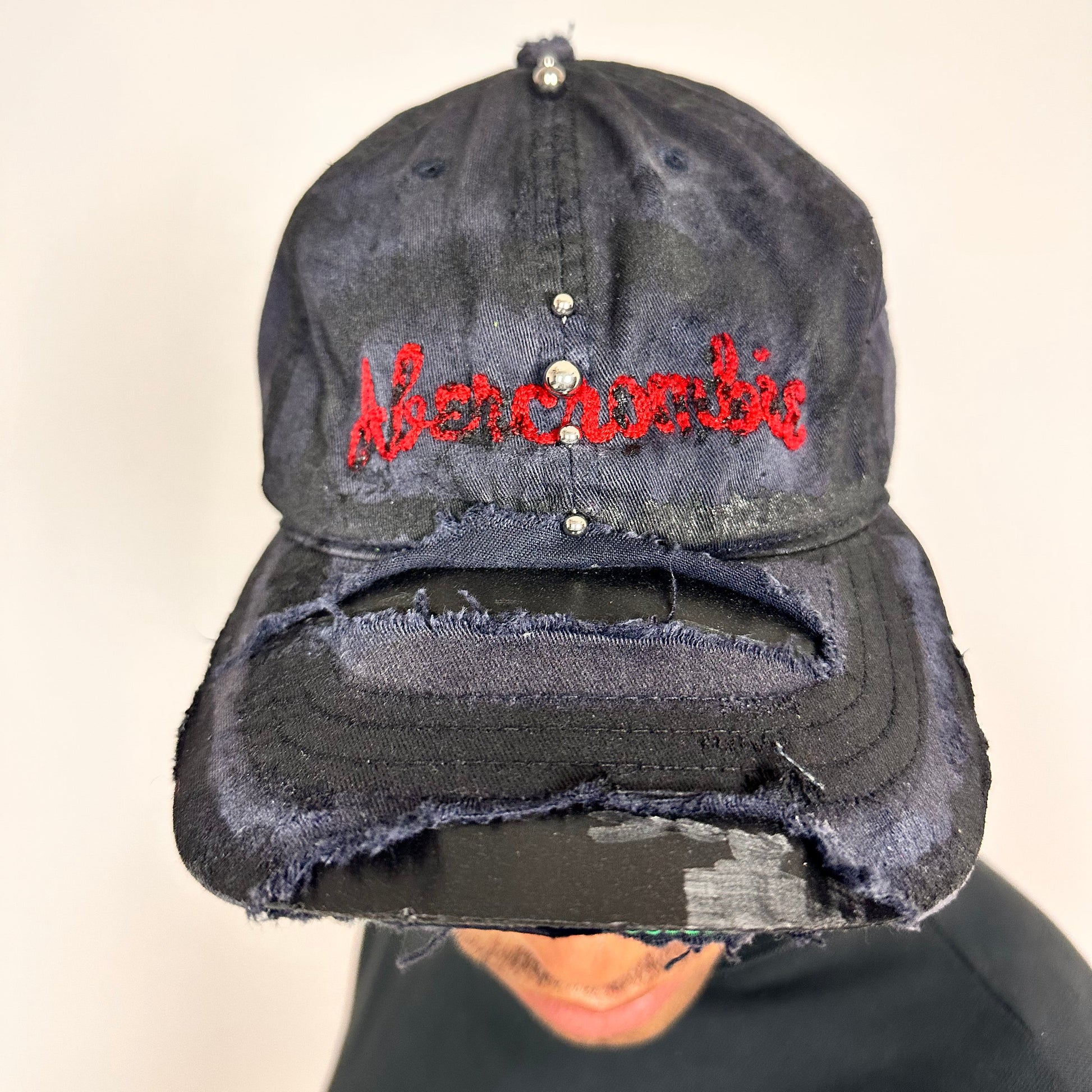 Front of Navy ASTROBOI* x Abercrombie hat with distressed paint, stainless steel piercings, and logo embroidery on front and back, customized in NYC.