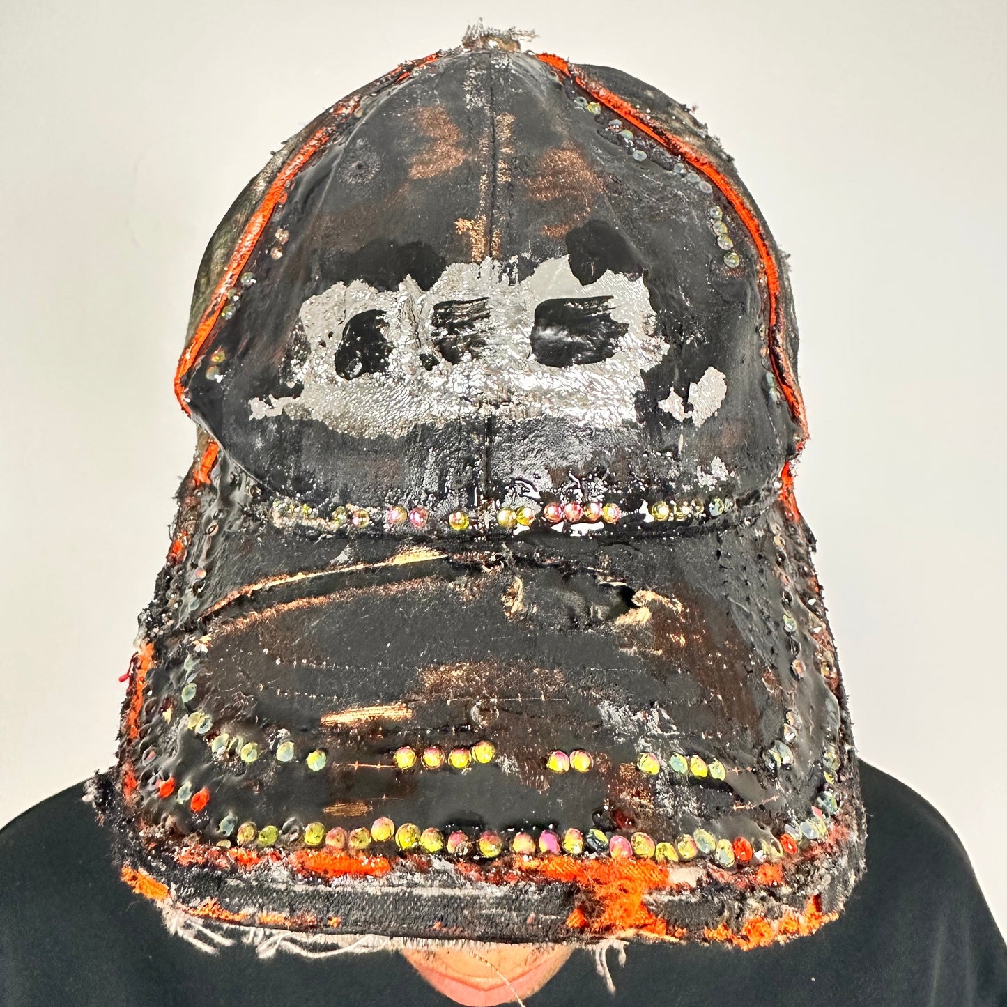 Front of ASTROBOI* brown camouflage distressed hat with rhinestones sealed in clear resin and custom hand-painted detailing.