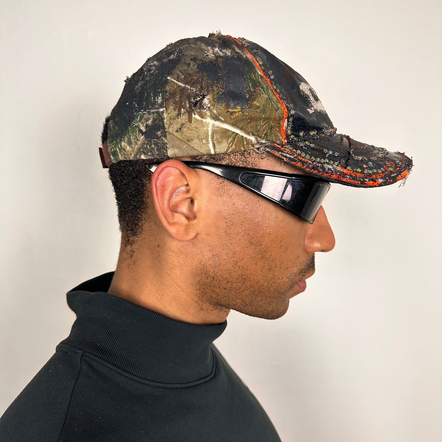 Right side of ASTROBOI* brown camouflage distressed hat with rhinestones sealed in clear resin and custom hand-painted detailing.