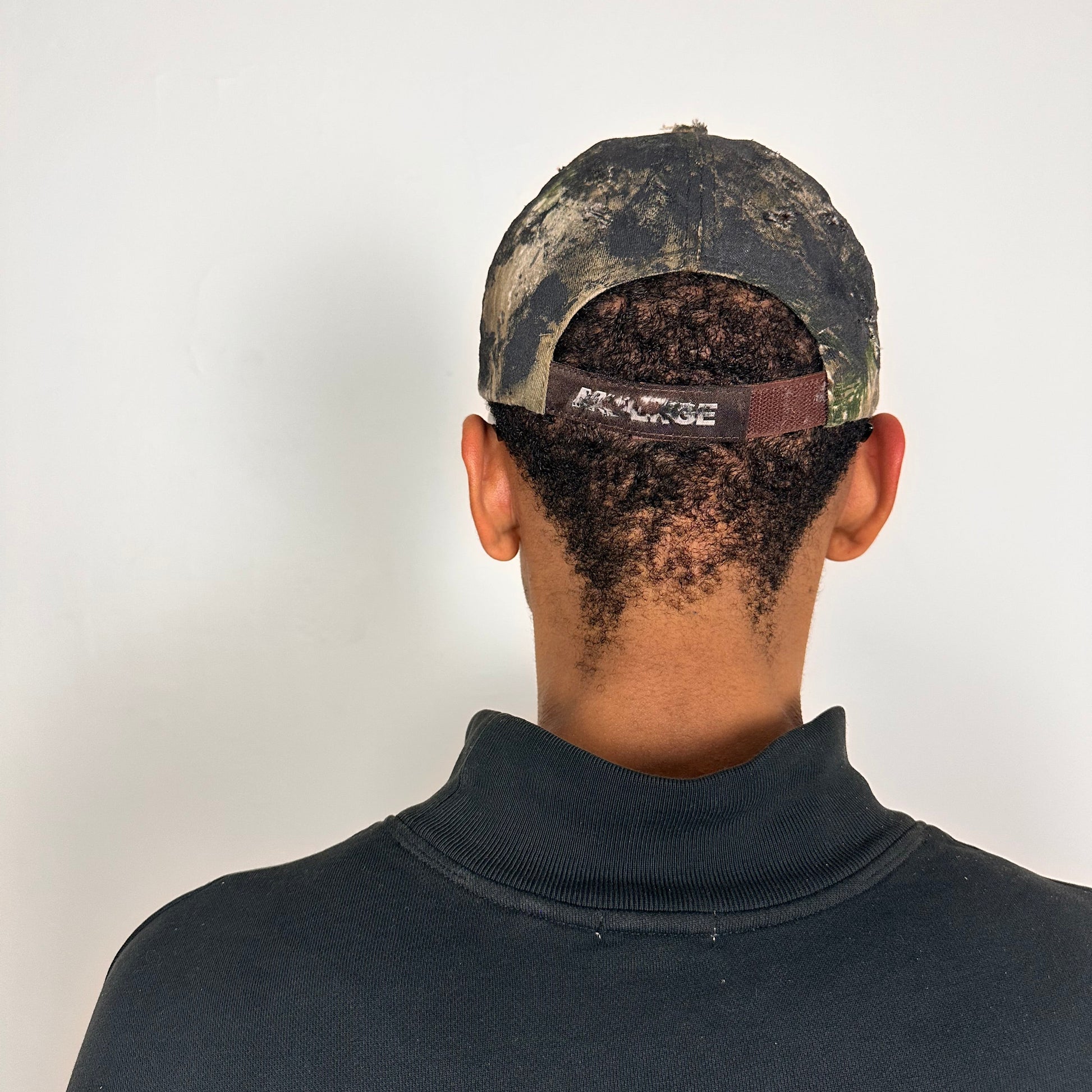 Back of ASTROBOI* brown camouflage distressed hat with rhinestones sealed in clear resin and custom hand-painted detailing.