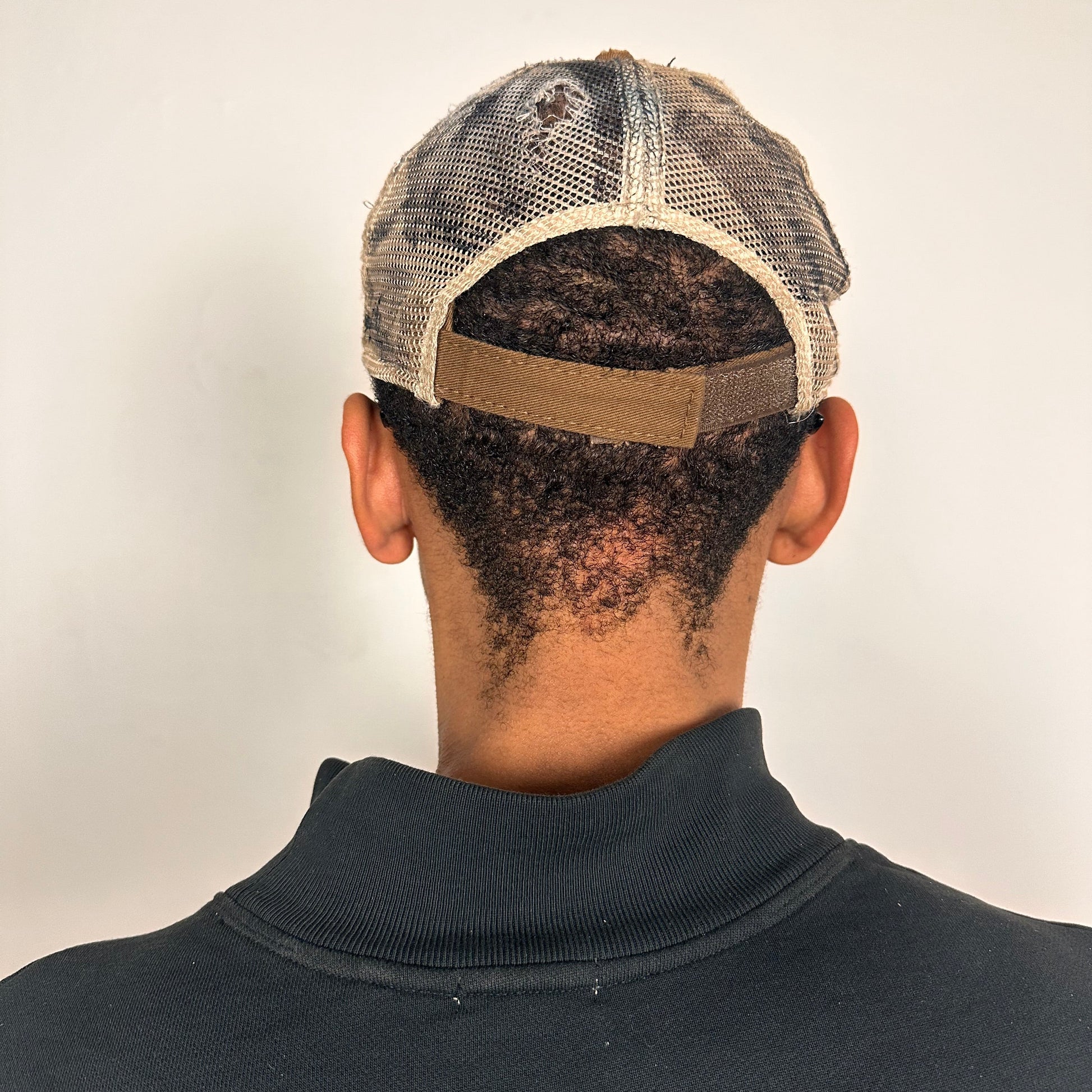 Back of ASTROBOI* x John Deere black and blue distressed trucker hat with rhinestone resin logo and stainless steel piercings.