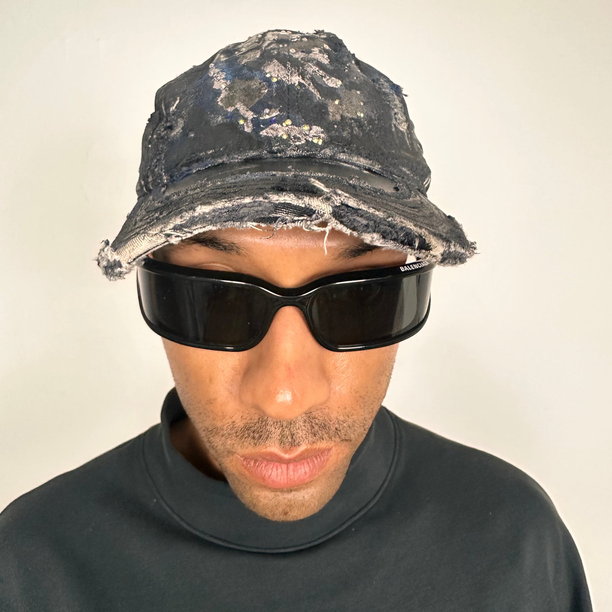 Front overview image of Black acid-washed denim hat with silver paint accents, multicolored rhinestones, and a ripped visor seam, customized by ASTROBOI* STUDIO.