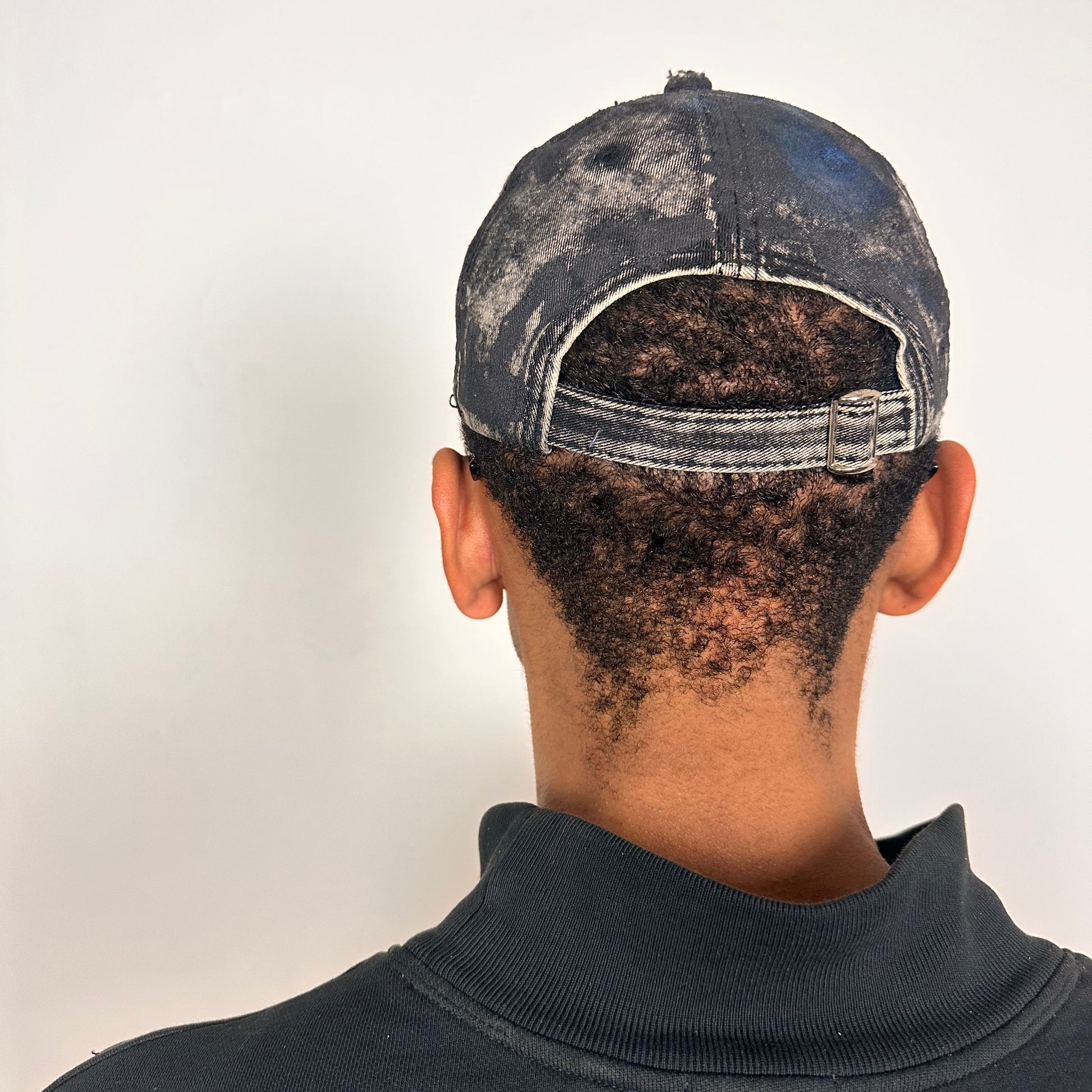 Back side of Black acid-washed denim hat with silver paint accents, multicolored rhinestones, and a ripped visor seam, customized by ASTROBOI* STUDIO.