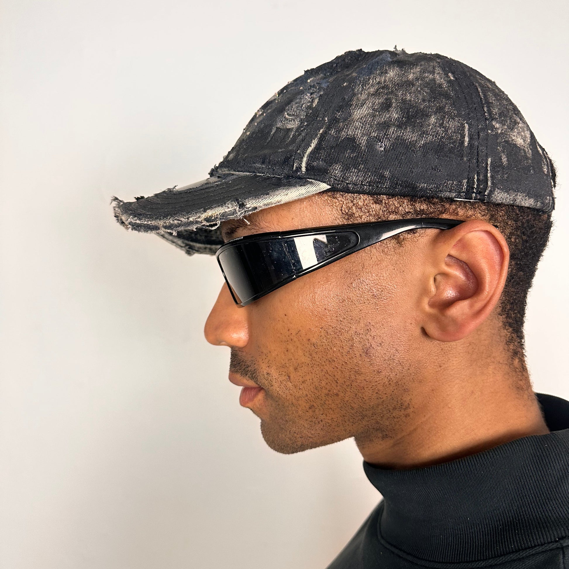 Left side of Black acid-washed denim hat with silver paint accents, multicolored rhinestones, and a ripped visor seam, customized by ASTROBOI* STUDIO.