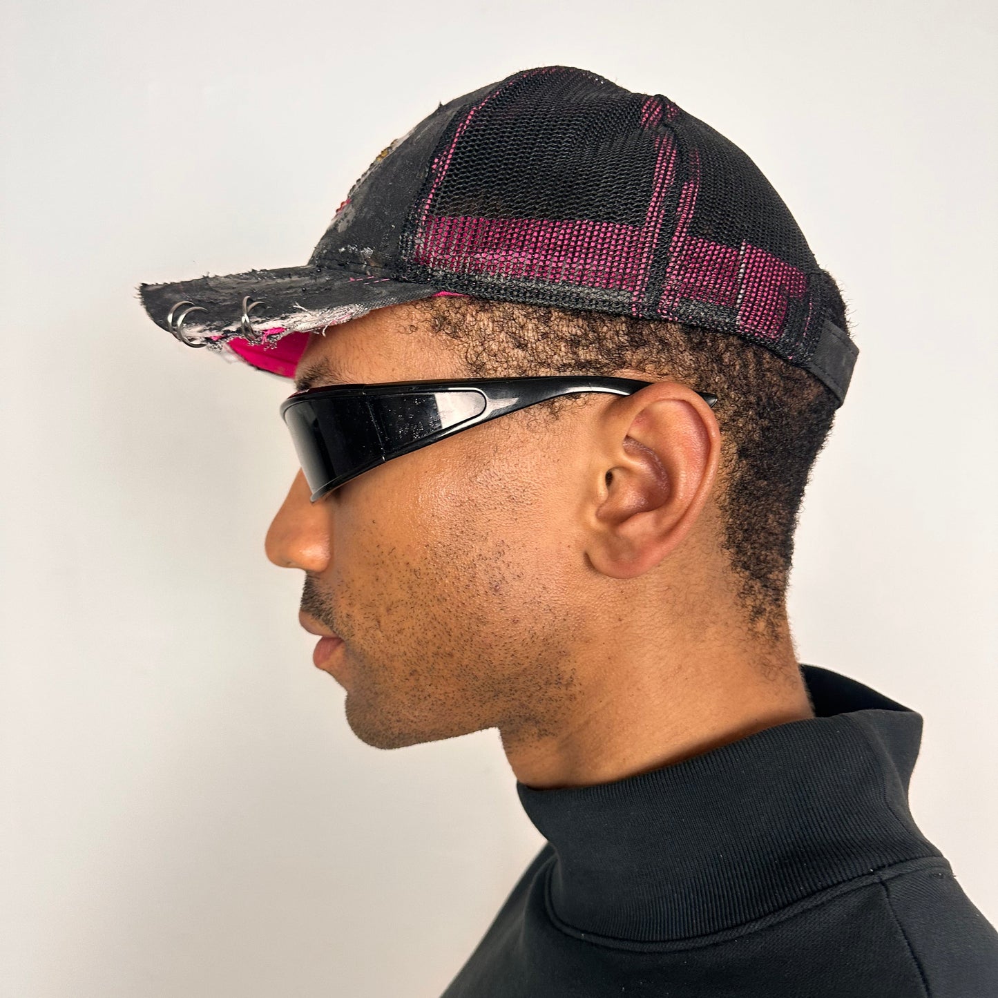 Left side of ASTROBOI* x Mossy Oak black and pink distressed rhinestone hat with resin logo and mesh back panel