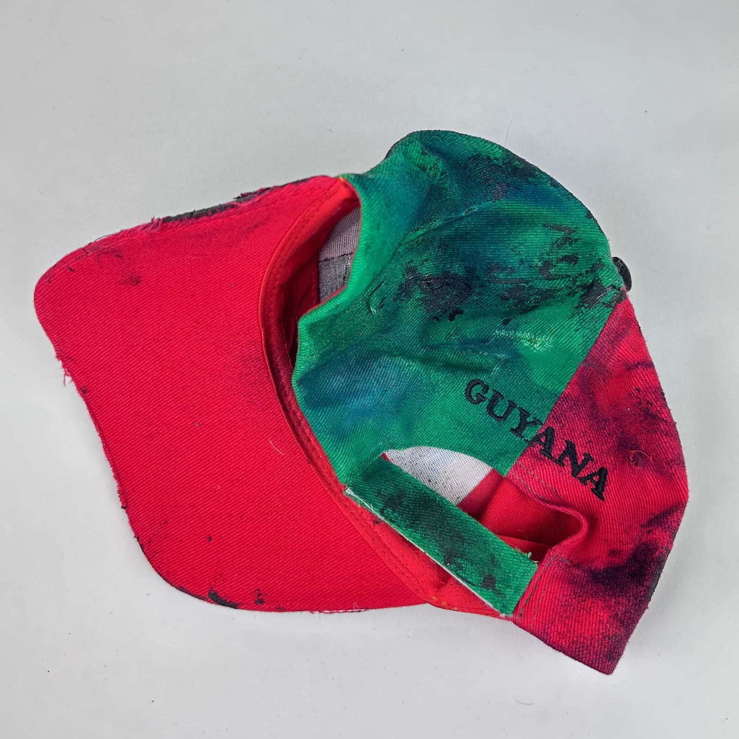 Back product shot of ASTROBOI* Guyana yellow red green distressed baseball hat with resin-sealed rhinestone logo patch and adjustable strap, hand-customized in NYC