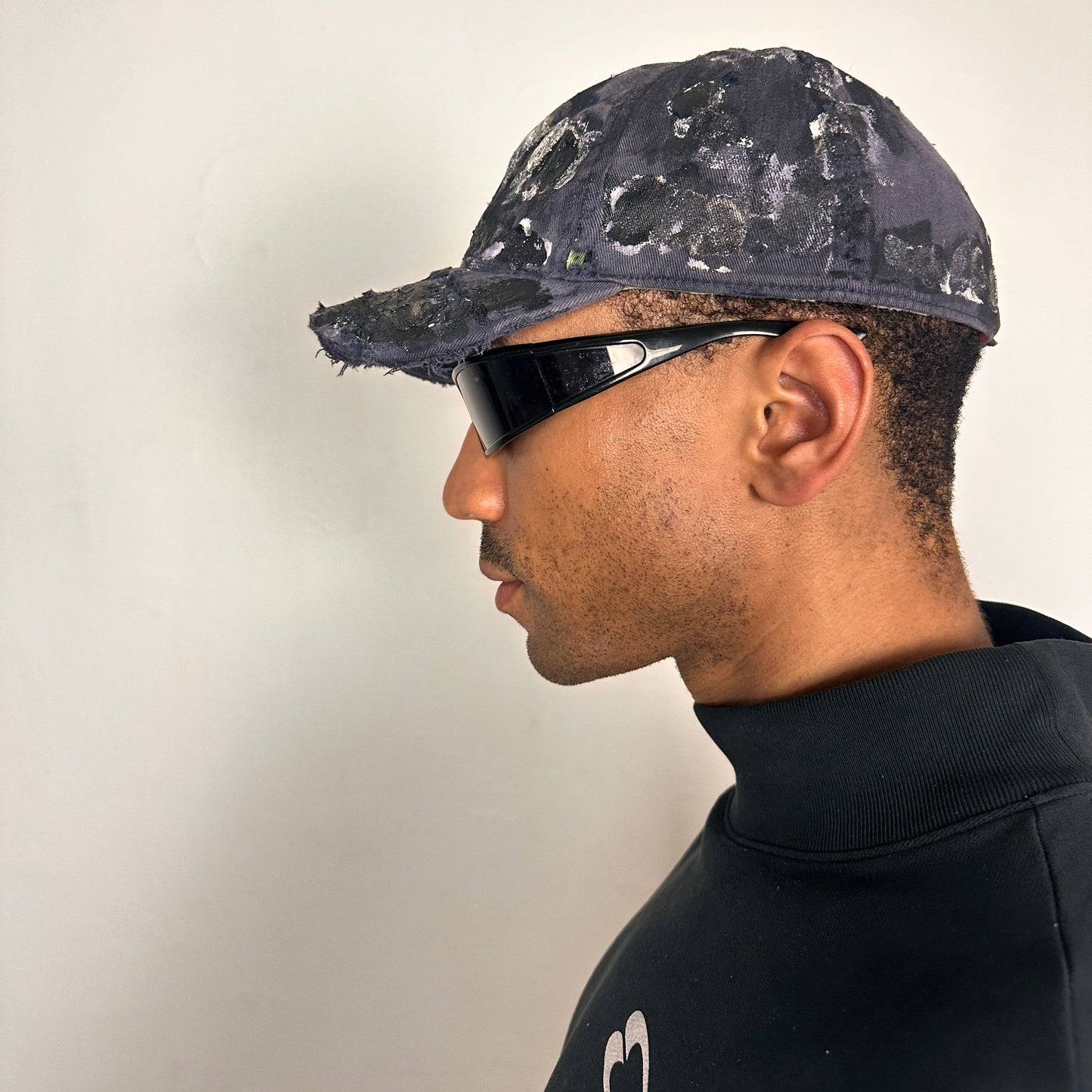 Left of ASTROBOI* navy fitted cap with custom black, white, and silver paint and distressed vintage finish.