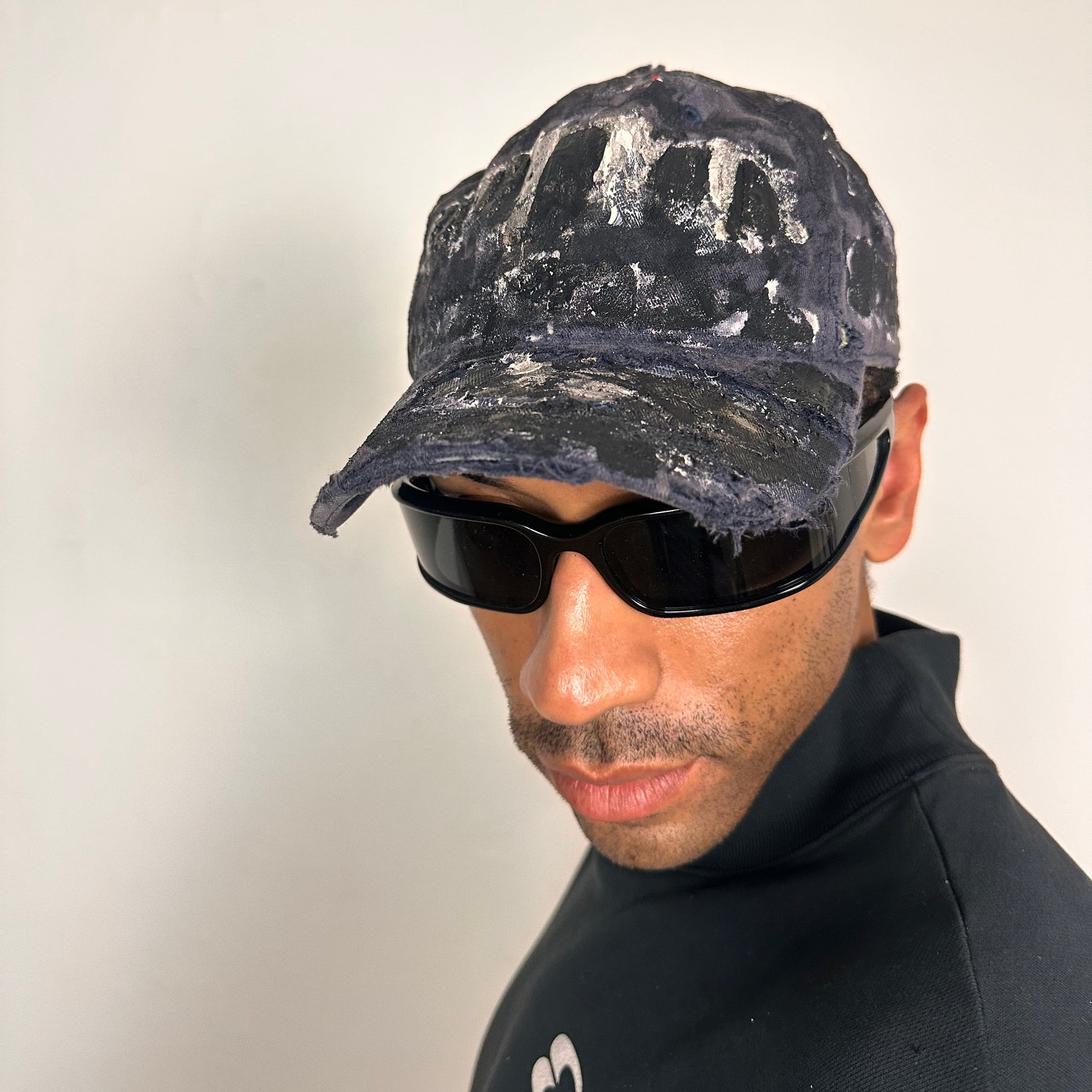 Front left of ASTROBOI* navy fitted cap with custom black, white, and silver paint and distressed vintage finish.