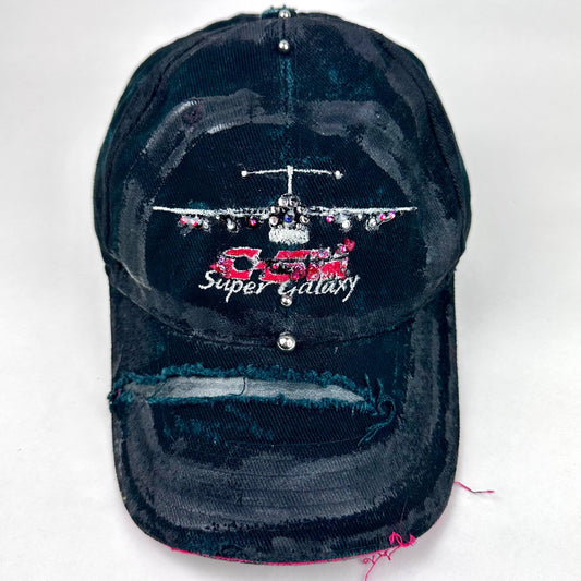 Front product shot of ASTROBOI* C5M Super Galaxy black baseball cap with resin-sealed rhinestone logo patch and adjustable strap, hand-customized in NYC