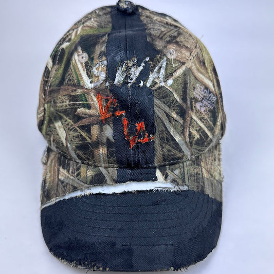 Front of ASTROBOI* x Mossy Oak brown RealTree camouflage tattoo hat with SWA embroidery, black painted distressing, youth size, custom NYC piece