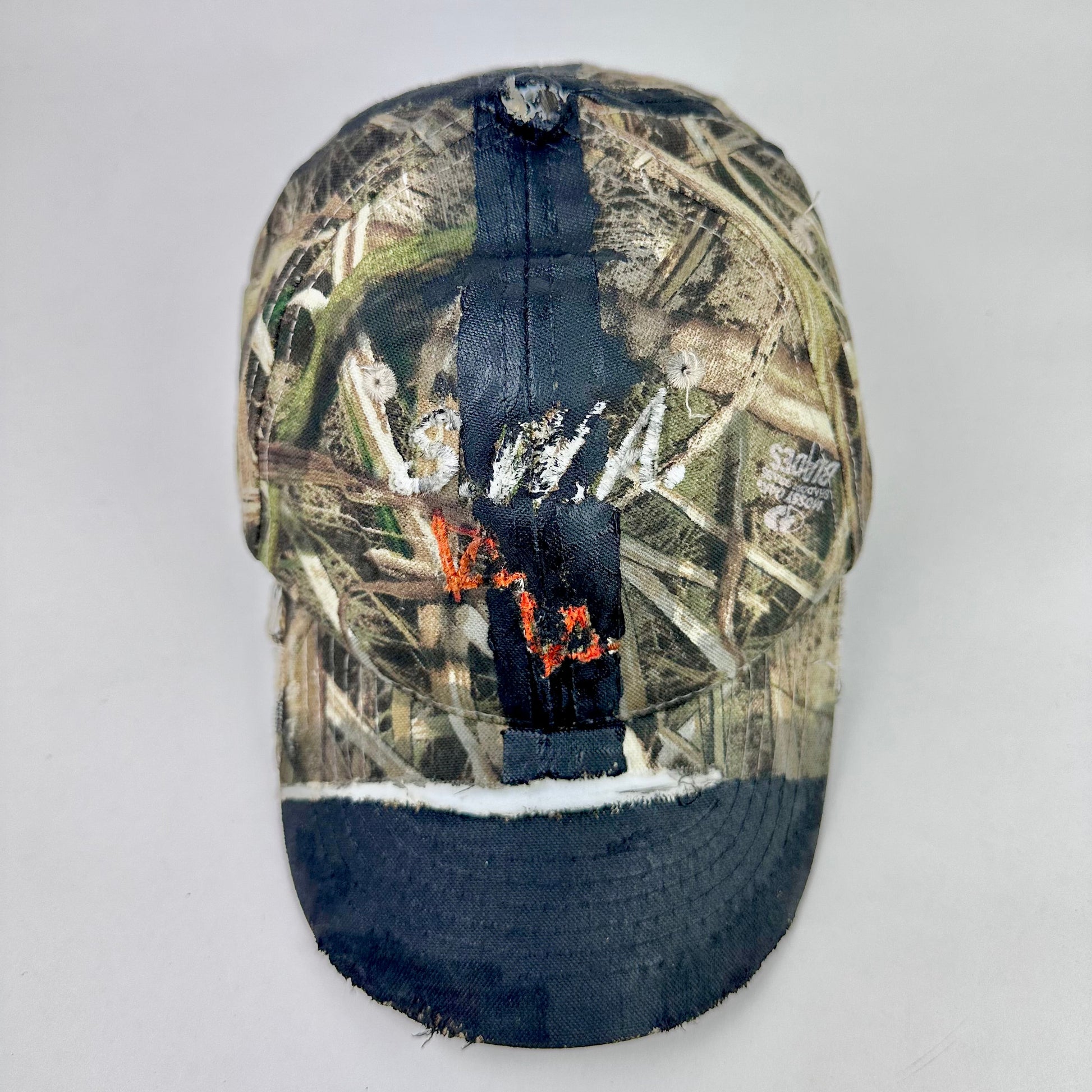 Camouflage cap with black brim on a light gray background