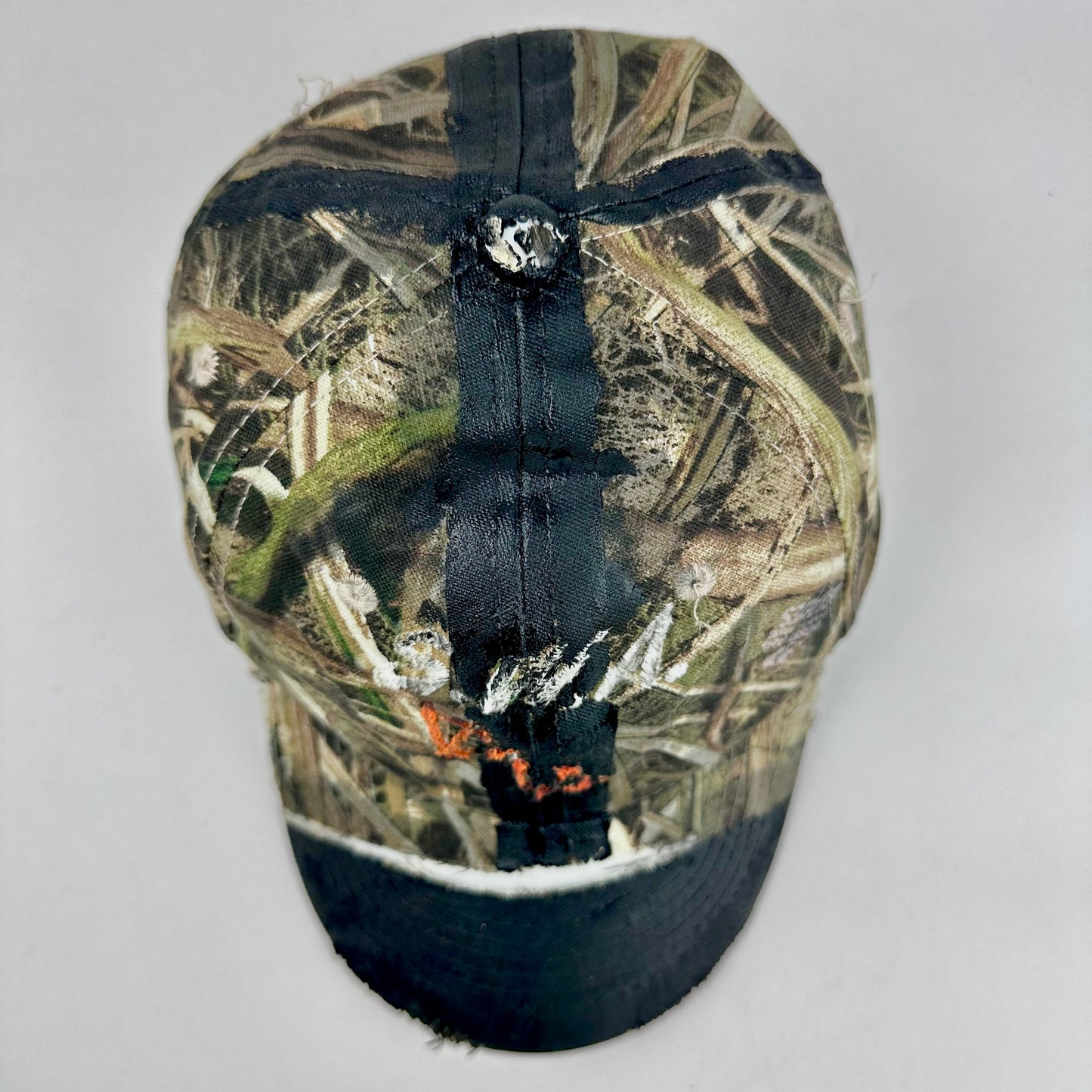 Top of ASTROBOI* x Mossy Oak brown RealTree camouflage tattoo hat with SWA embroidery, black painted distressing, youth size, custom NYC piece
