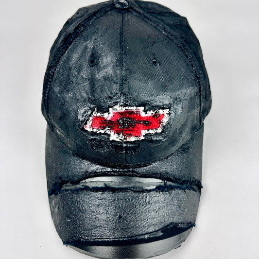 Still life front of ASTROBOI* x Chevy black distressed baseball hat with resin-sealed rhinestone logo, deconstructed visor, wax-painted tattoo details, adjustable fit