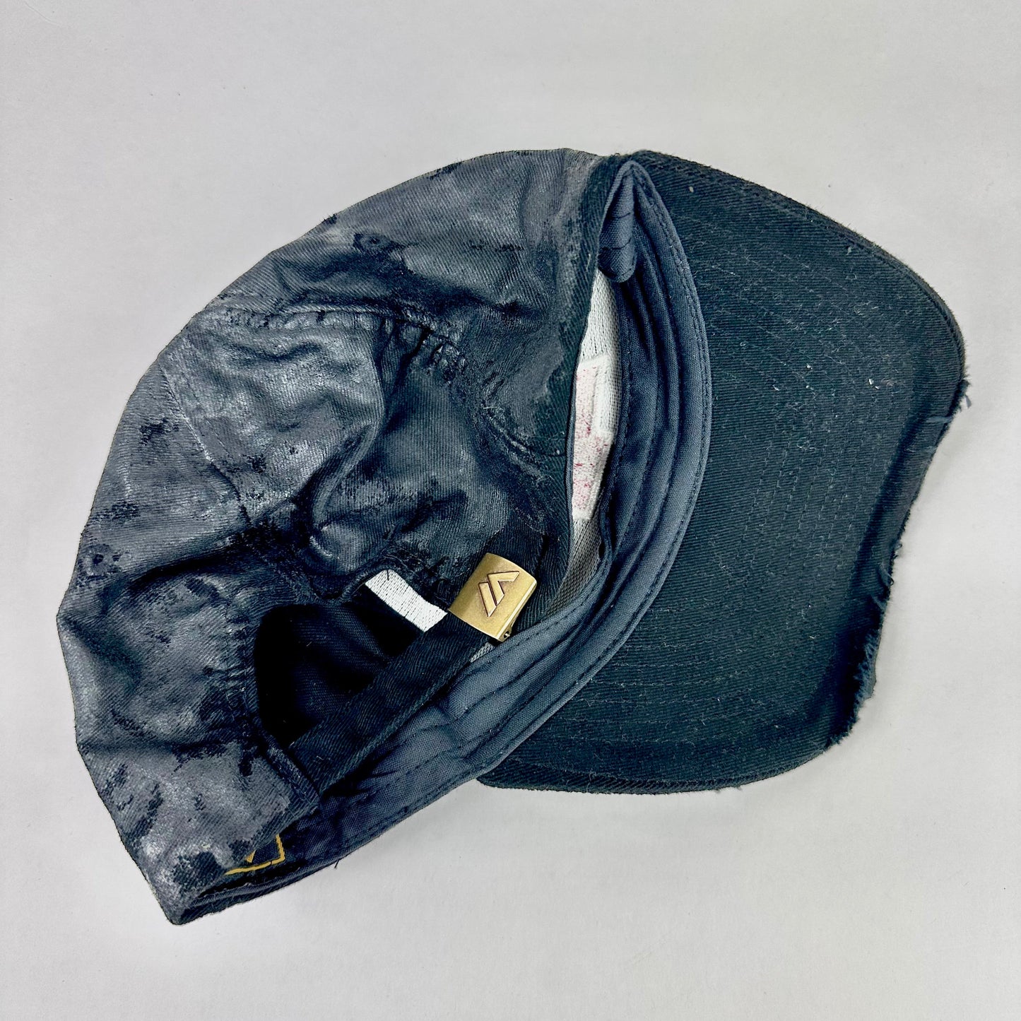Flat lay back of ASTROBOI* x Chevy black distressed baseball hat with resin-sealed rhinestone logo, deconstructed visor, wax-painted tattoo details, adjustable fit
