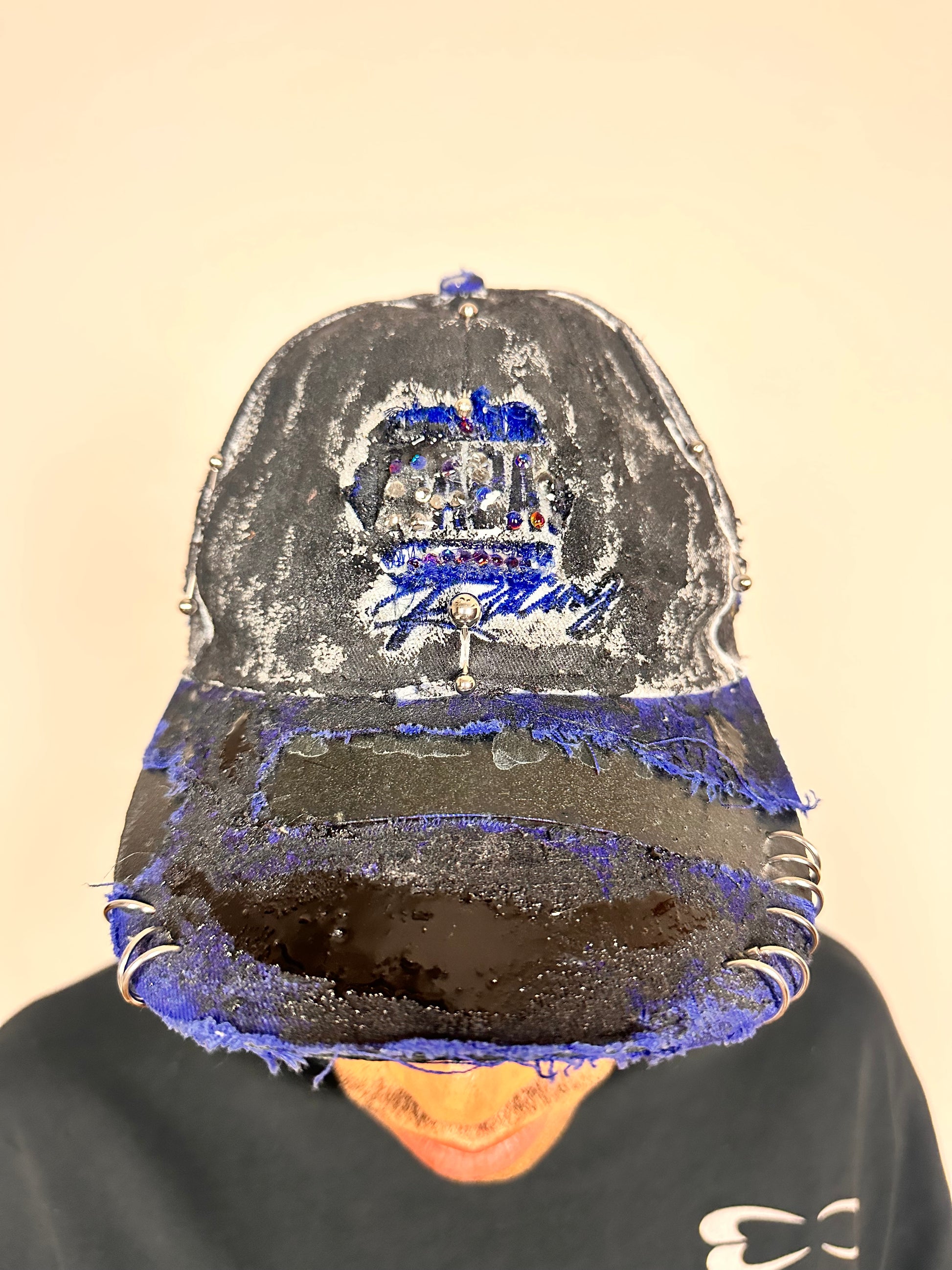 Front overview of Blue and white ASTROBOI* NAPA hat with rhinestone-covered logo sealed in clear resin, stainless steel piercings, and a deconstructed visor, handcrafted in NYC.